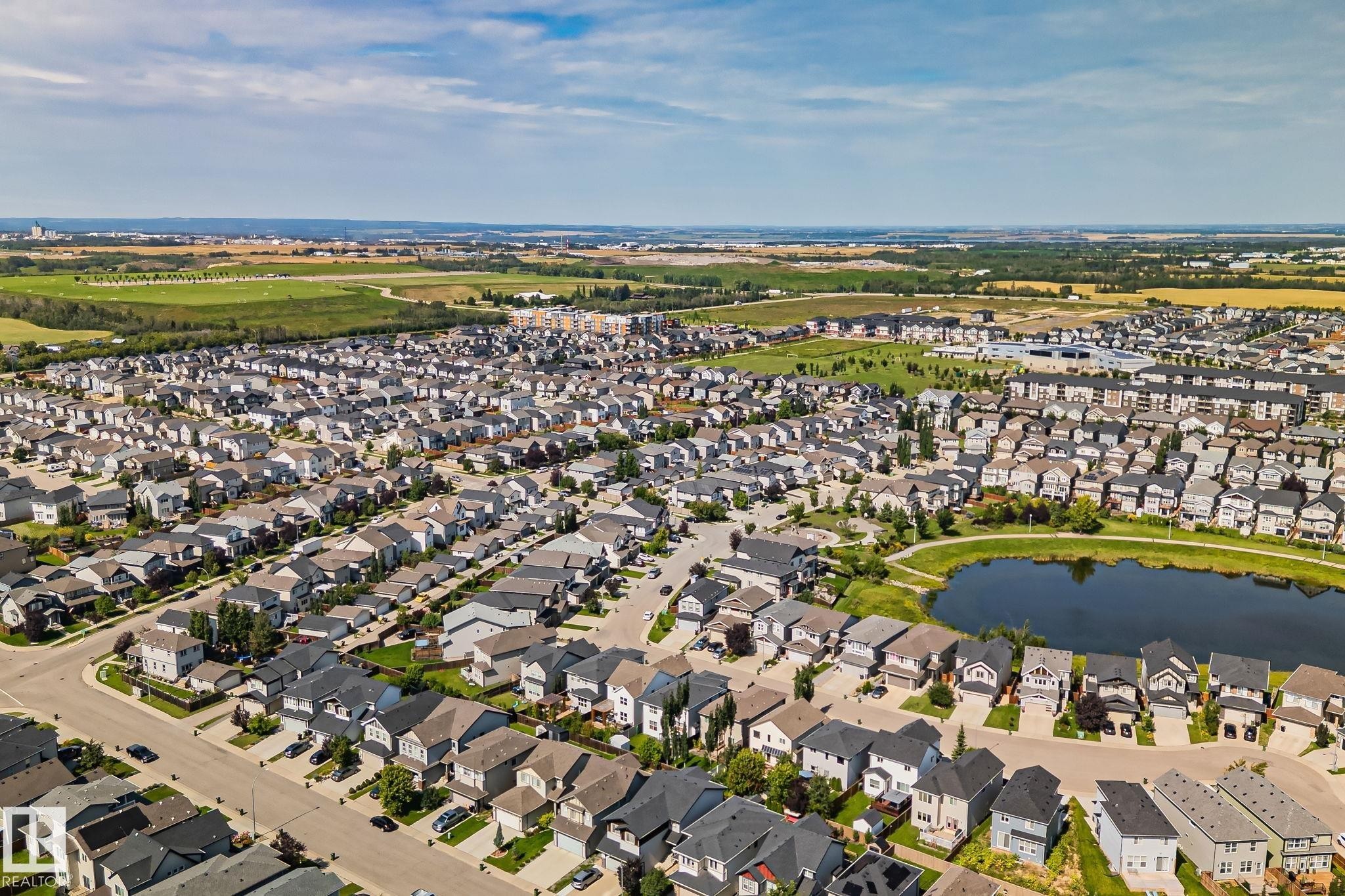 Residential neighborhood featuring a central pond, surrounding green space, and varied home styles - 1337 Secord Landing Nw, Edmonton, AB - Outdoor With Body Of Water With View