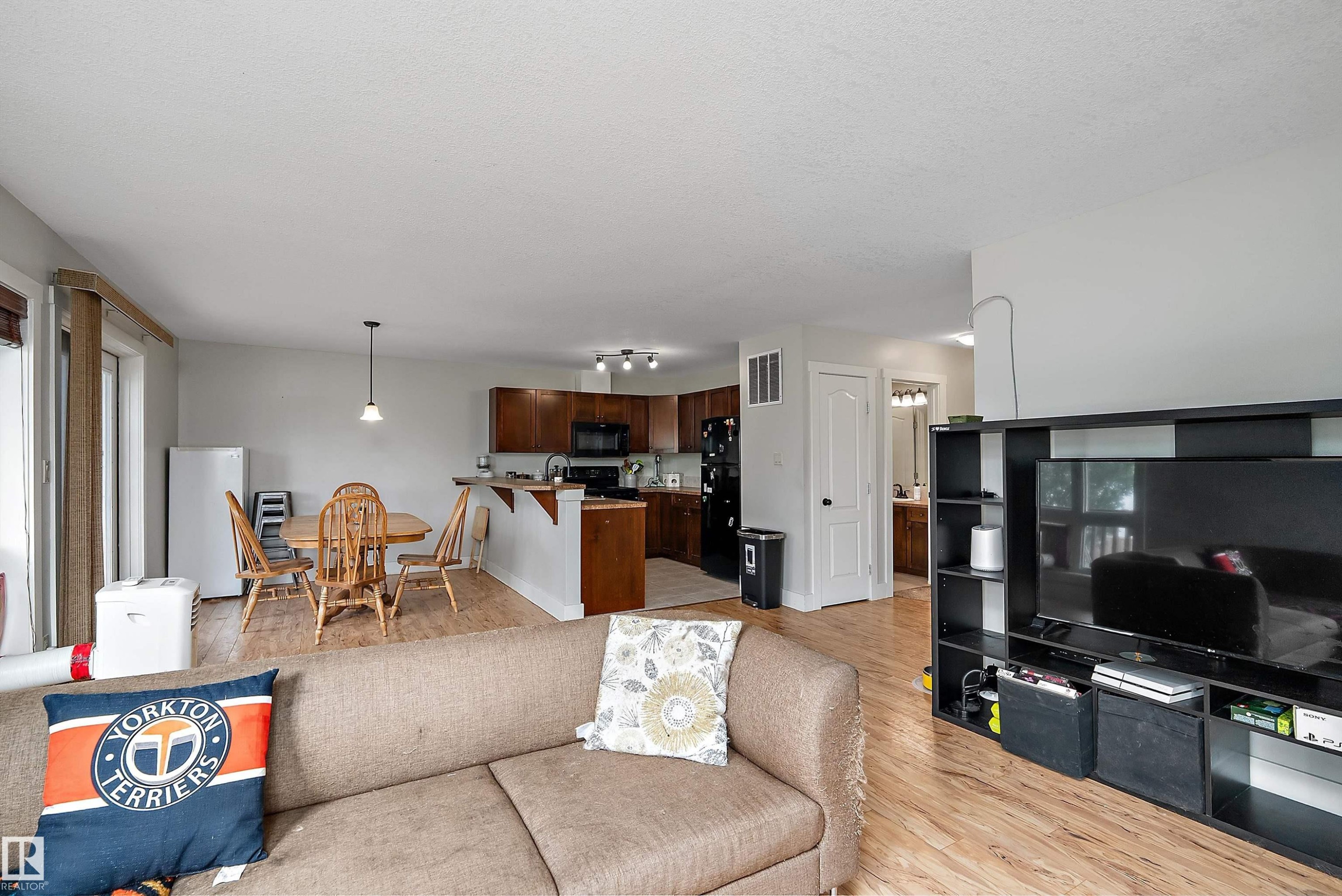 Open-concept living space featuring wood-finish flooring, a kitchen with dark cabinetry, and a dining area - 203 Graybriar Green, Stony Plain, AB - Indoor Photo Showing Living Room