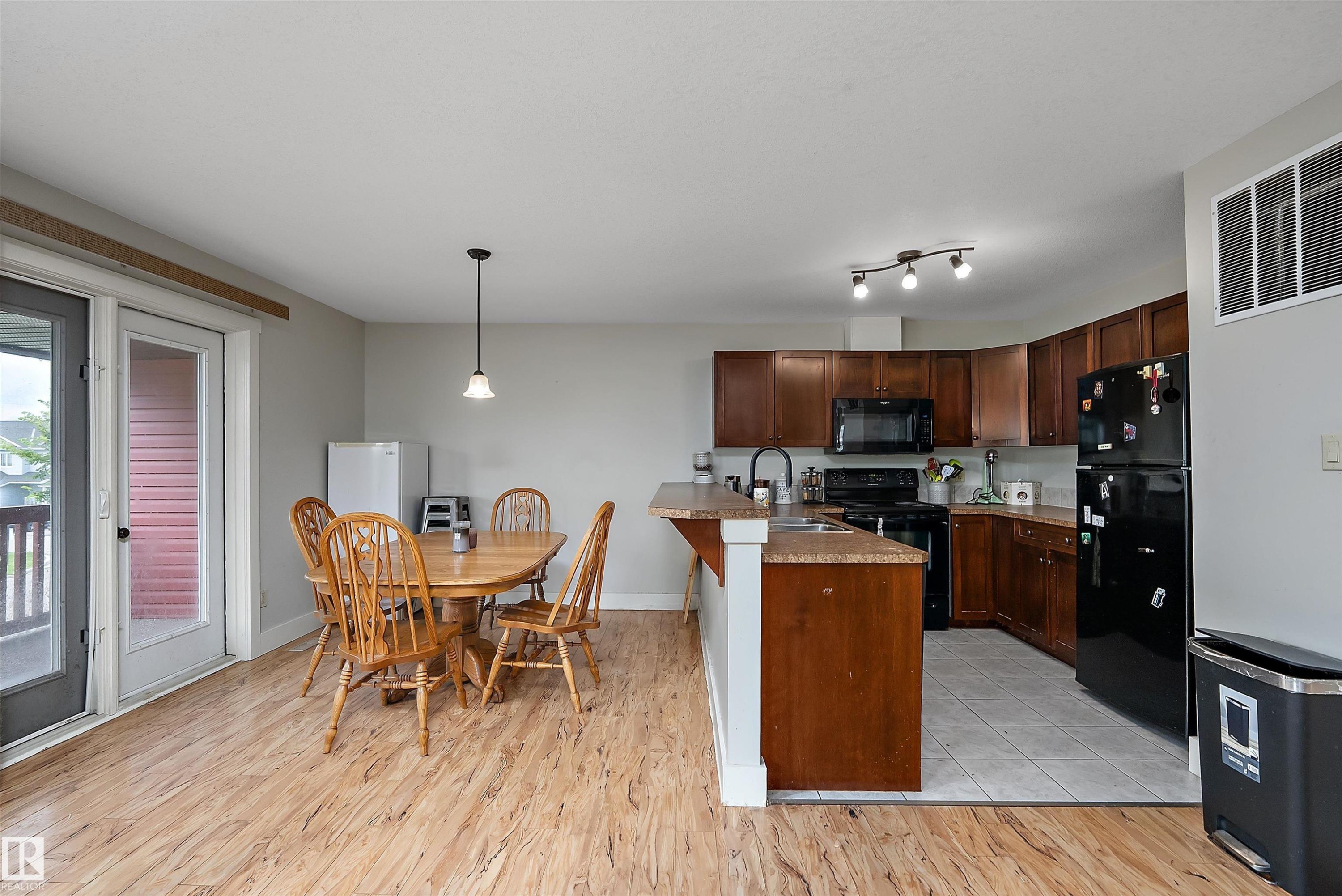Kitchen featuring dark wood-finish cabinetry, black appliances, and a peninsula with countertop seating - 203 Graybriar Green, Stony Plain, AB - Indoor