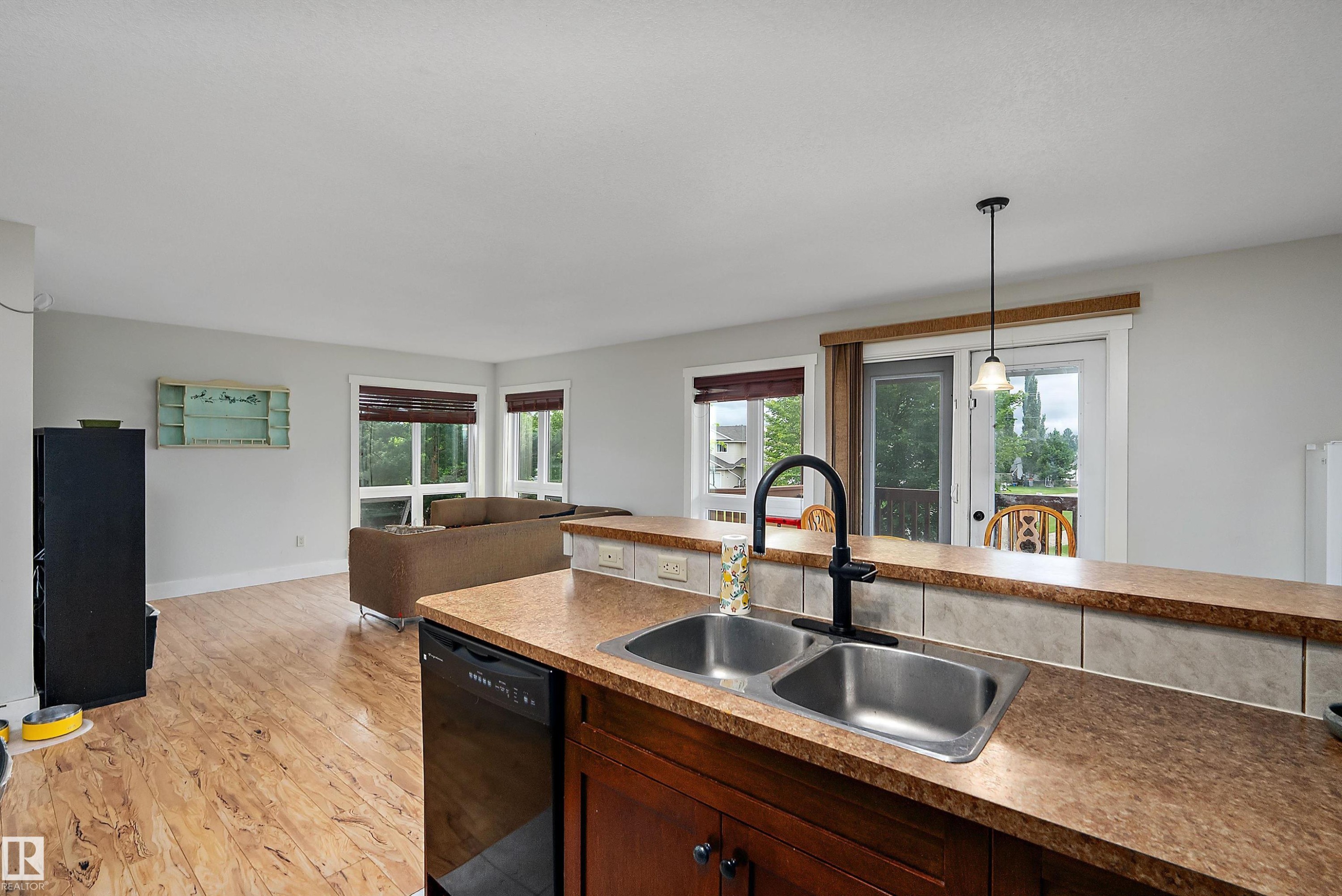 Kitchen island with a double basin stainless steel sink, black gooseneck faucet, and dark wood-finish cabinetry - 203 Graybriar Green, Stony Plain, AB - Indoor Photo Showing Kitchen With Double Sink