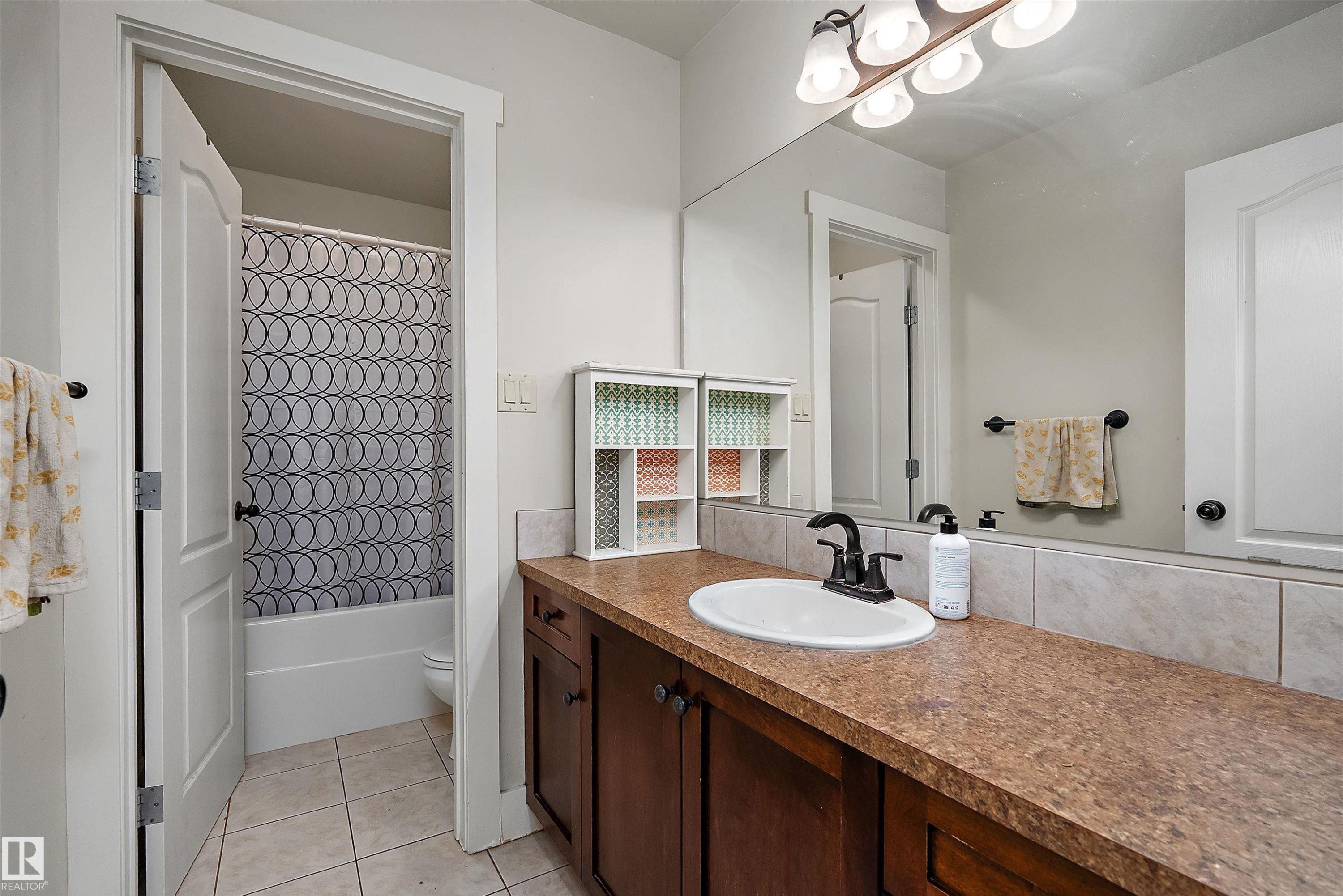 Vanity with built-in cabinetry, integrated sink, and an expansive mirror - 203 Graybriar Green, Stony Plain, AB - Indoor Photo Showing Bathroom