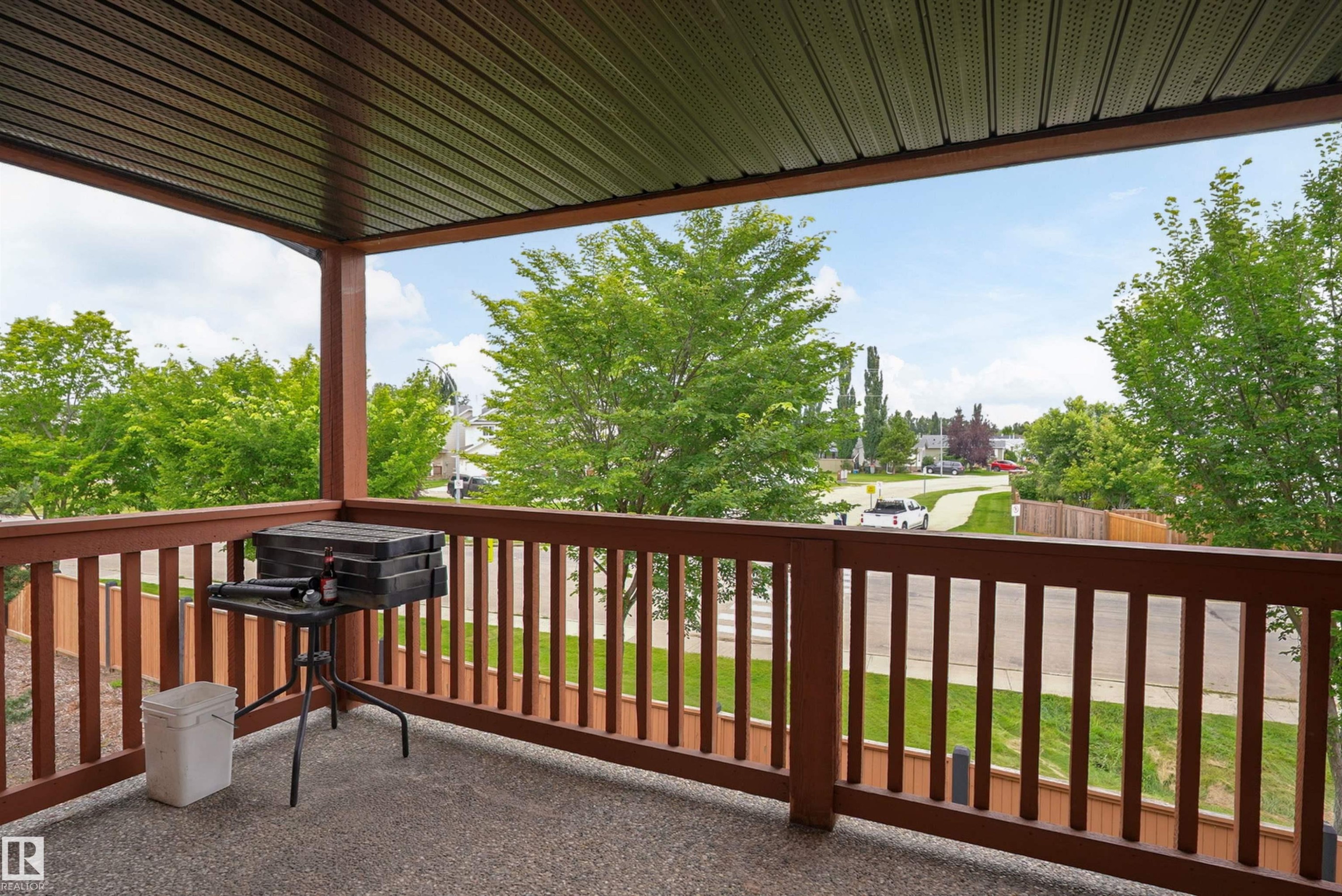 Covered outdoor balcony featuring a brown railing and a textured floor - 203 Graybriar Green, Stony Plain, AB - Outdoor With Exterior