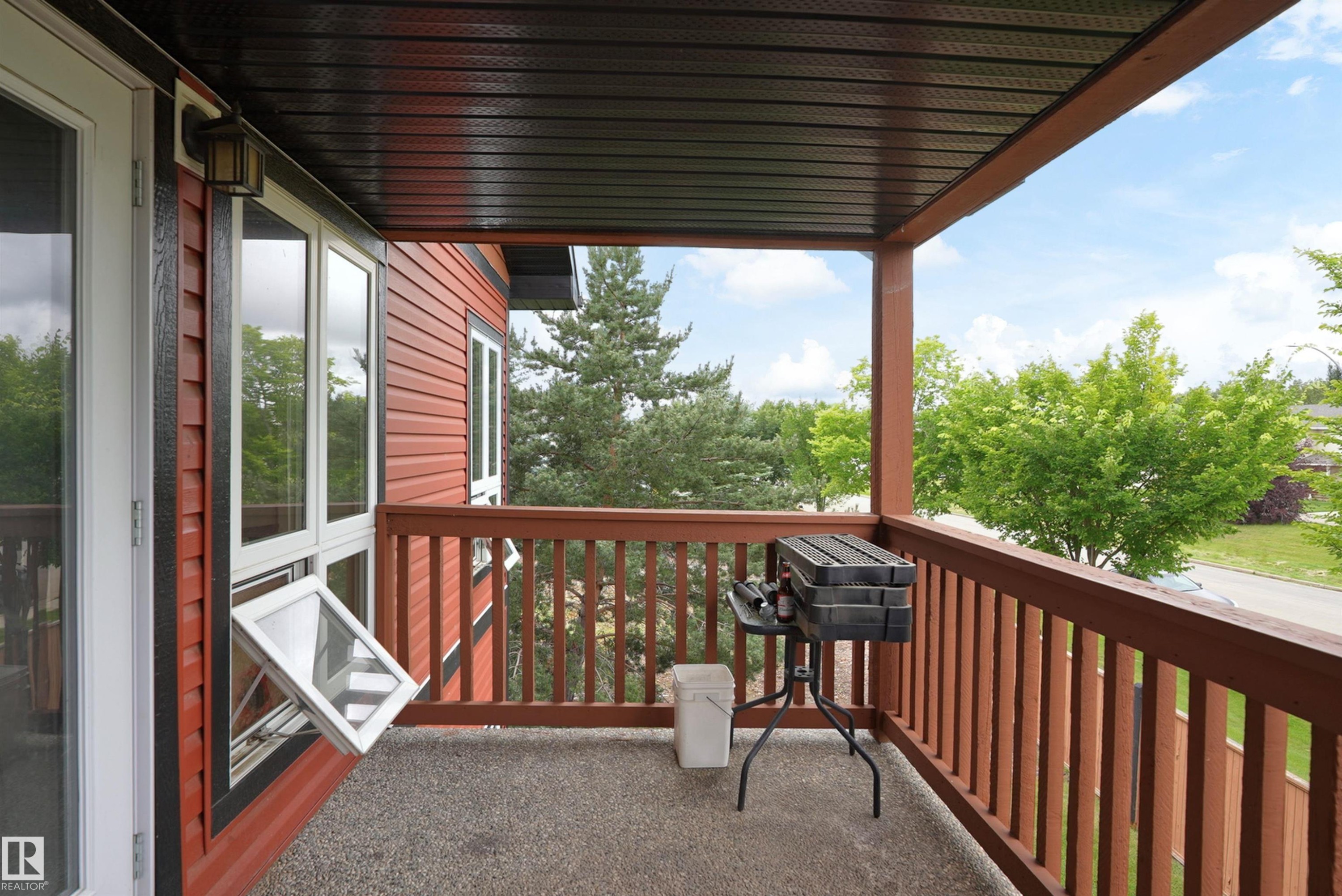 Covered balcony with a textured concrete surface, wood railing, and exterior wall siding - 203 Graybriar Green, Stony Plain, AB - Outdoor With Exterior