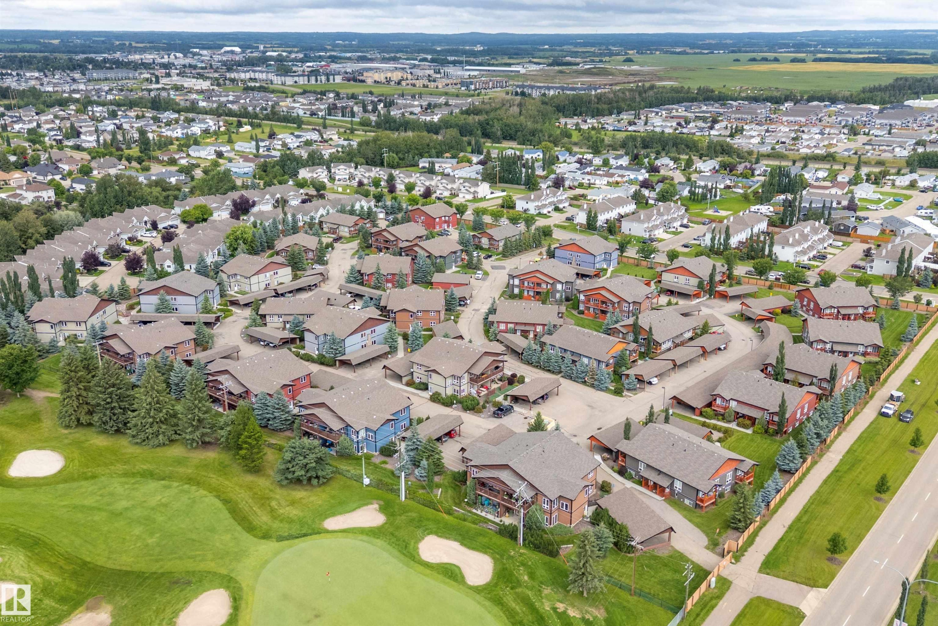 Residential development bordering a golf course, featuring multiple buildings with individual carports and surrounding green spaces - 203 Graybriar Green, Stony Plain, AB - Outdoor With View