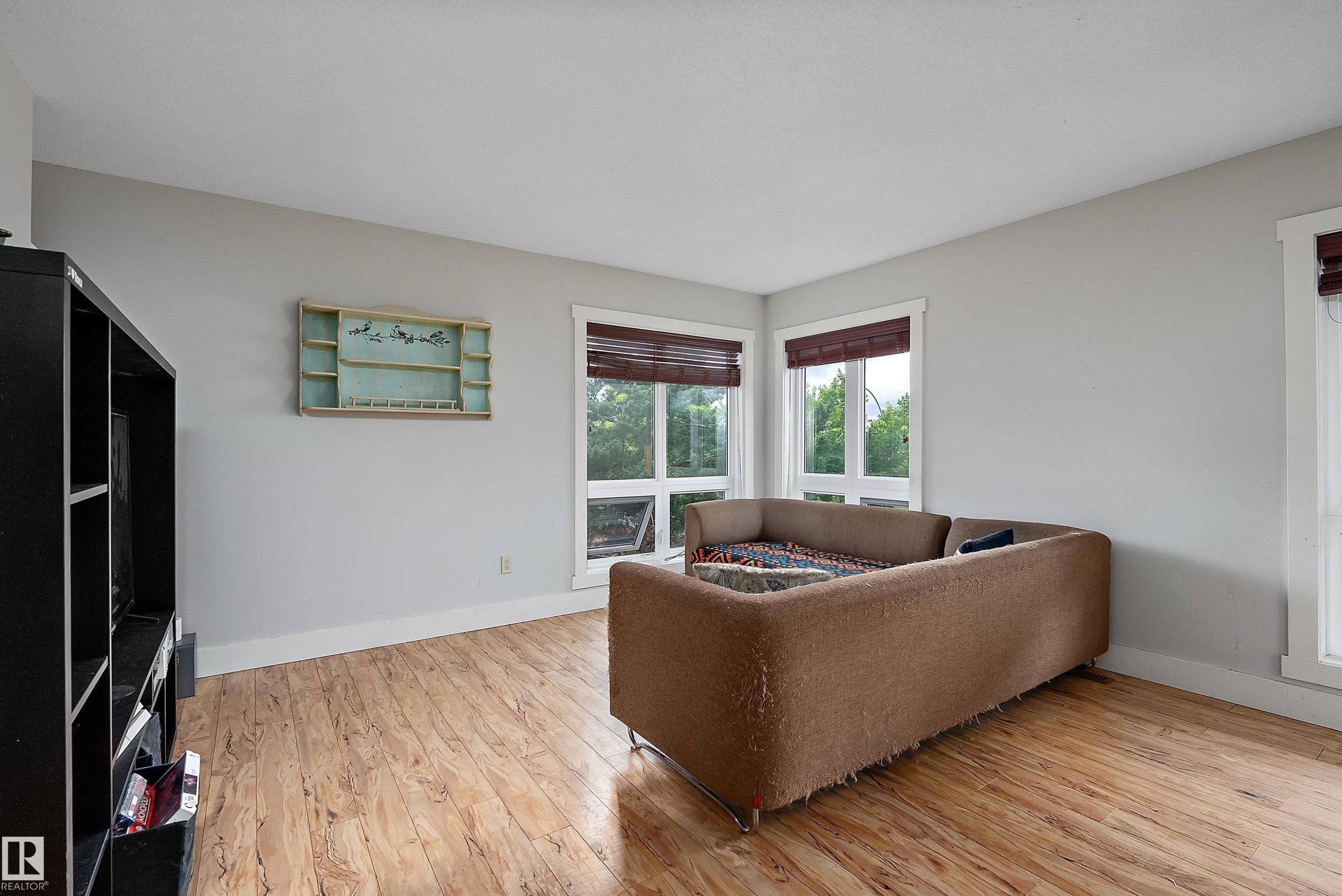 Light-toned walls, wood-finish flooring, corner windows with white trim, and dark window treatments - 203 Graybriar Green, Stony Plain, AB - Indoor Photo Showing Living Room