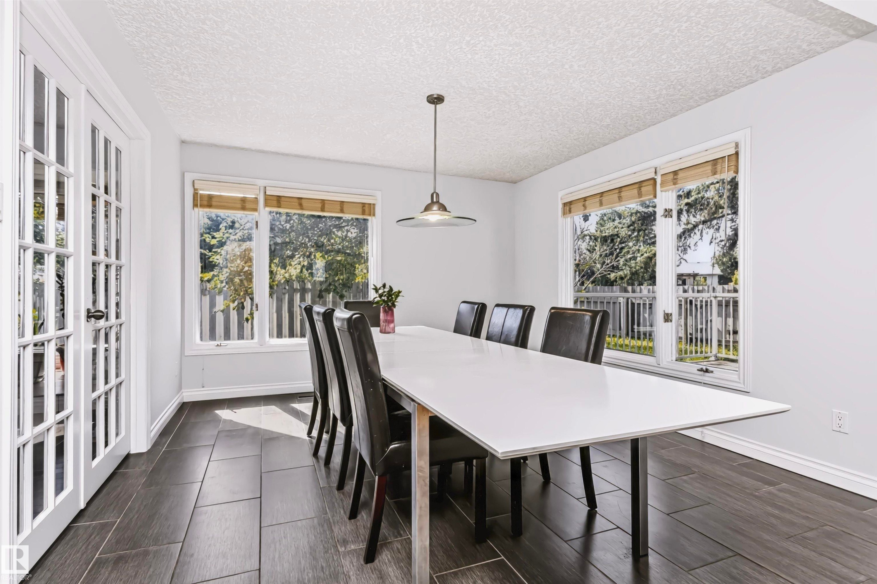 White interior walls with dark wood-finish tile flooring - 6016 177 Street Nw, Edmonton, AB - Indoor Photo Showing Dining Room