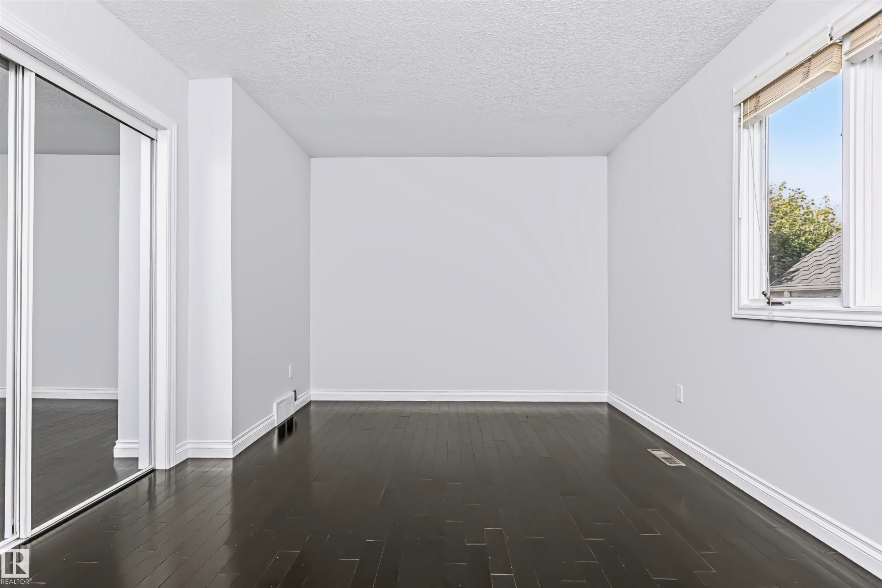 Dark wood-finish flooring, white trim, and a window with a white frame - 6016 177 Street Nw, Edmonton, AB - Indoor Photo Showing Other Room