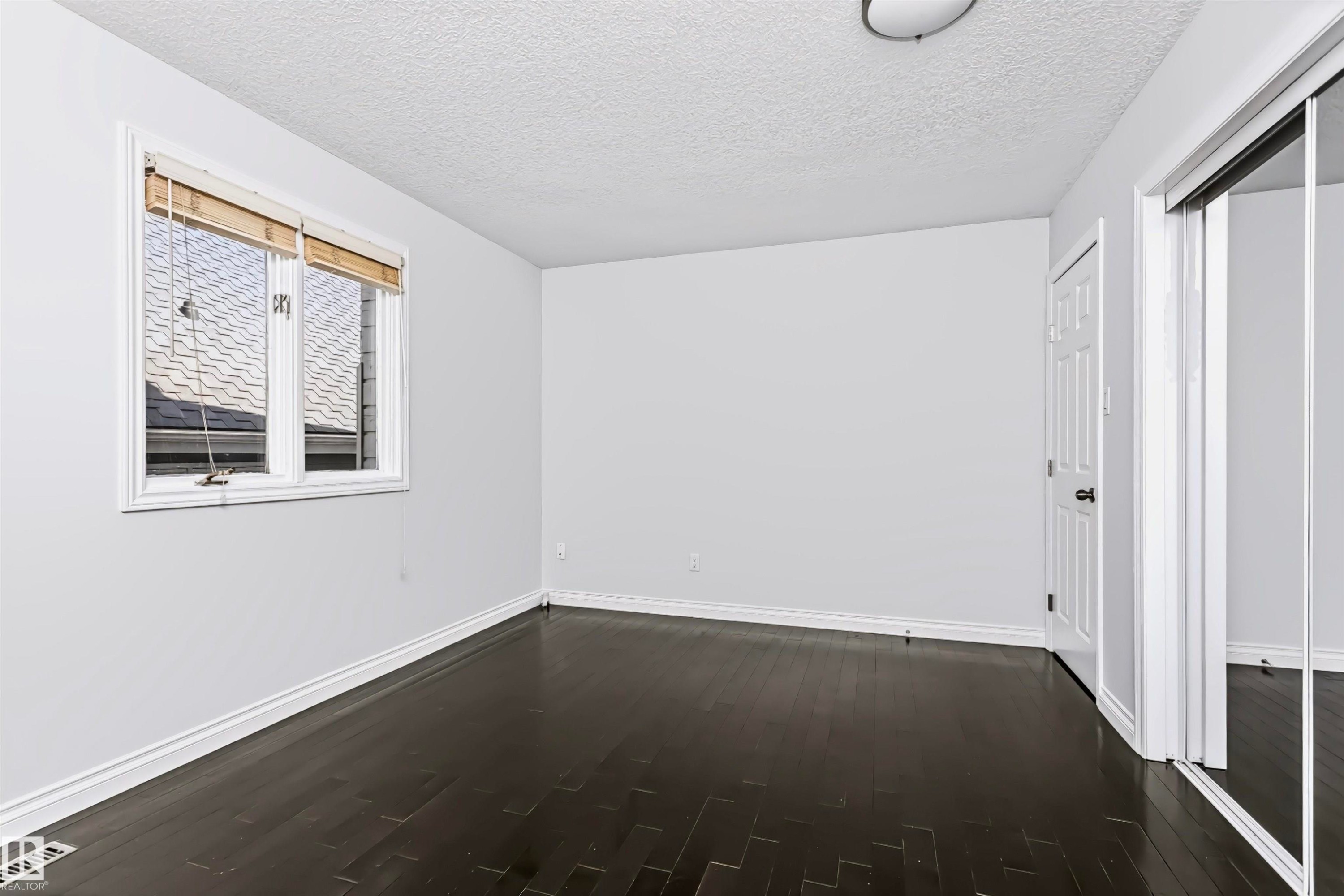 Dark wood-finish flooring, white trim, and a window with blinds - 6016 177 Street Nw, Edmonton, AB - Indoor Photo Showing Other Room