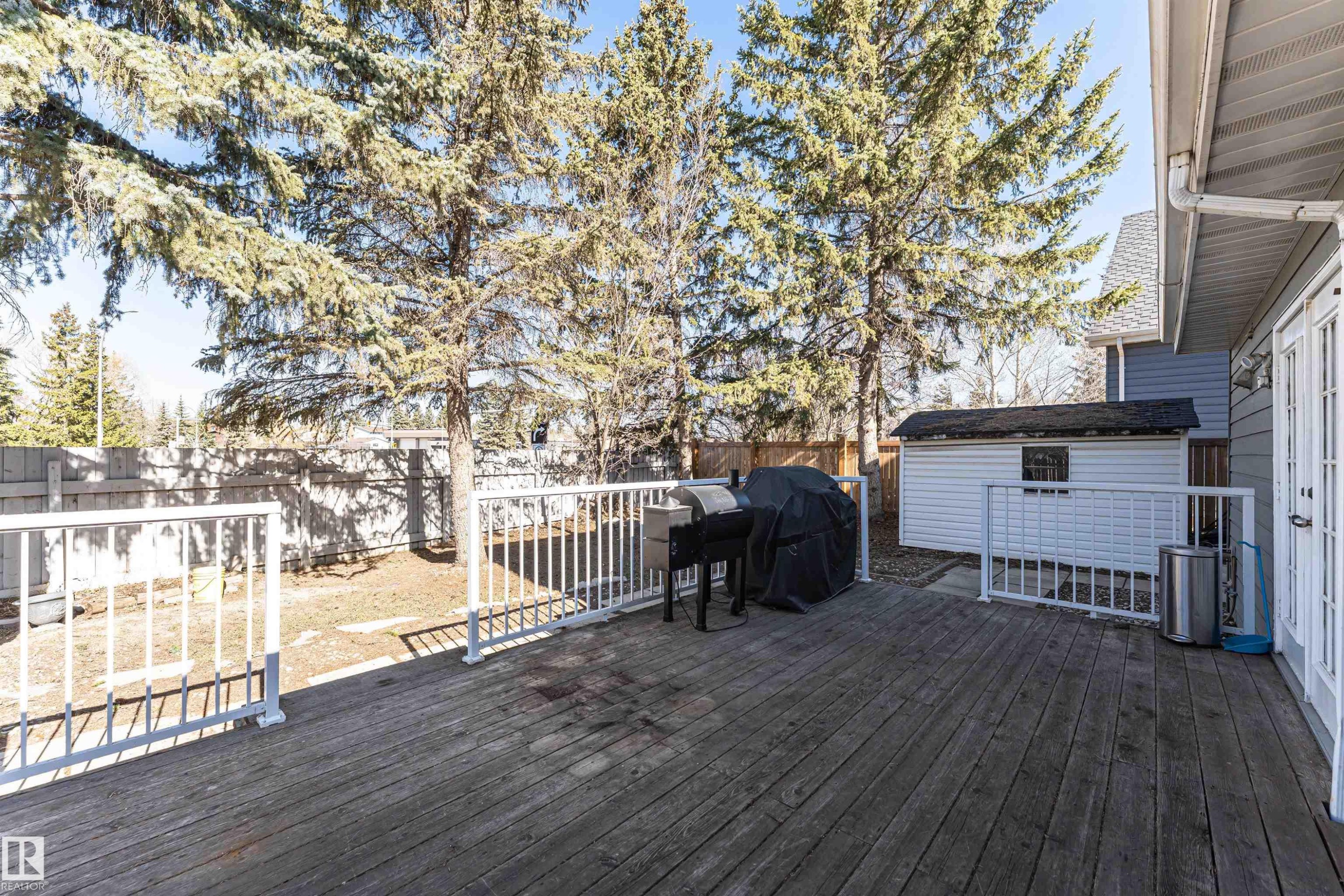 Spacious wood deck with white railings and French doors opening to the exterior - 6016 177 Street Nw, Edmonton, AB - Outdoor