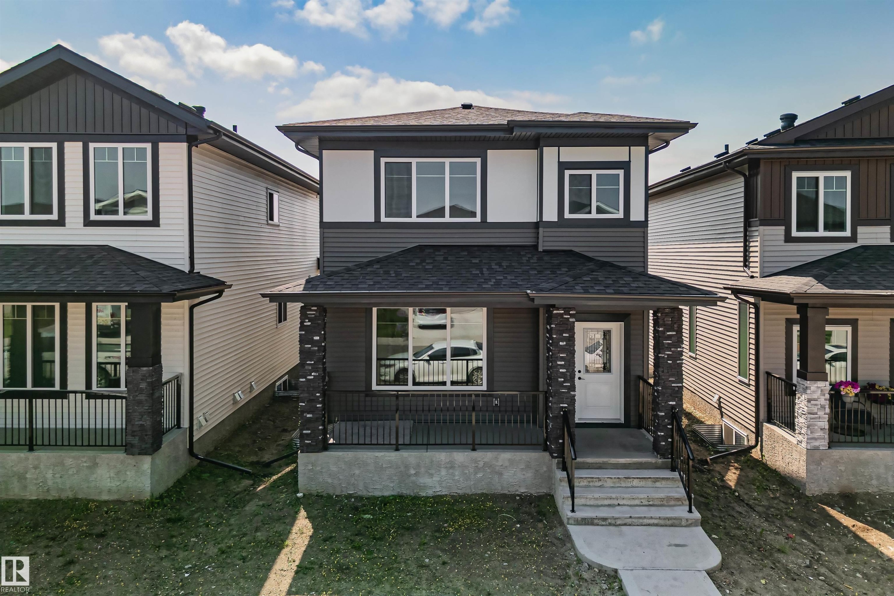 Two-story residence featuring a covered front porch, dark siding, white trim, and a concrete pathway to the entrance - 324 Roberts Wynd, Leduc, AB - Outdoor
