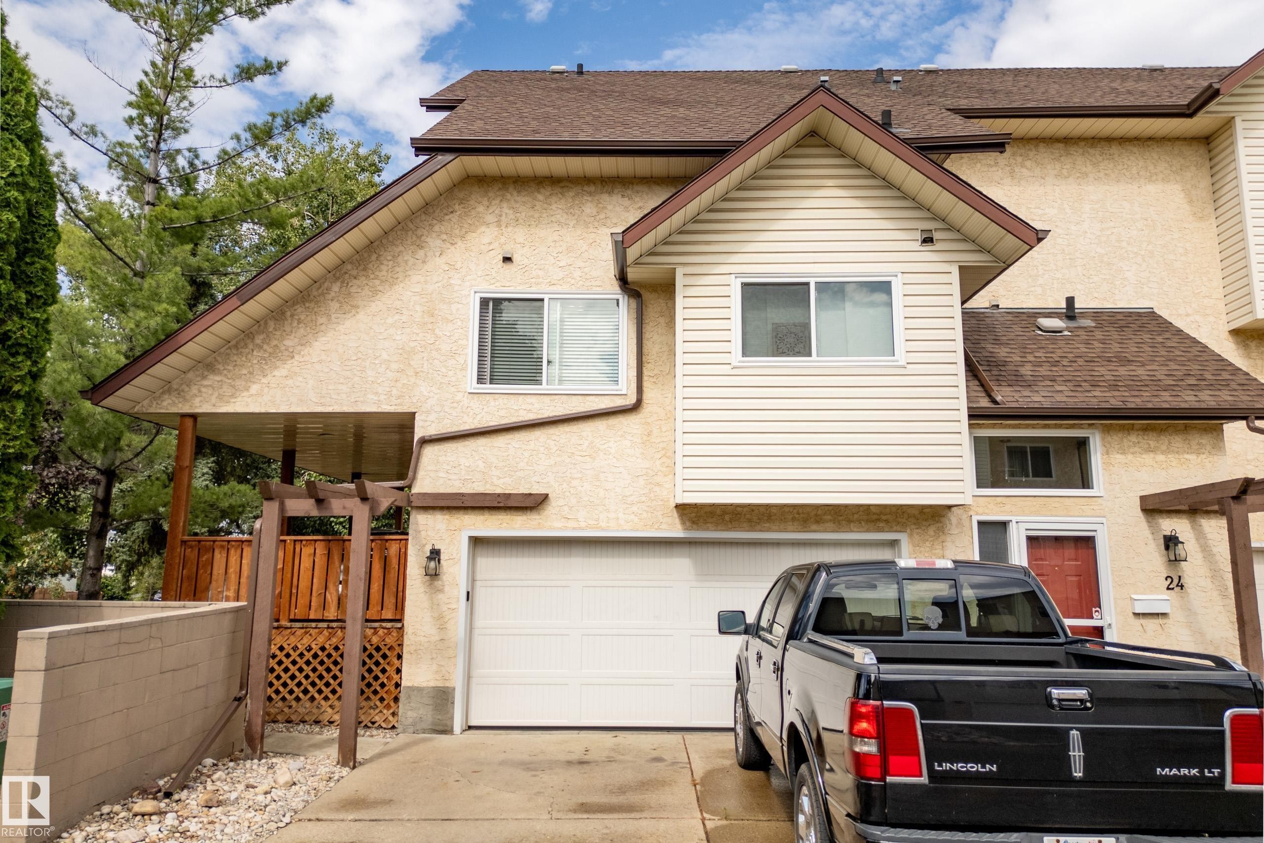 Stucco exterior with brown trim, attached garage, covered porch with wood lattice, and asphalt shingle roof - #25 3811 85 St Nw, Edmonton, AB - Outdoor