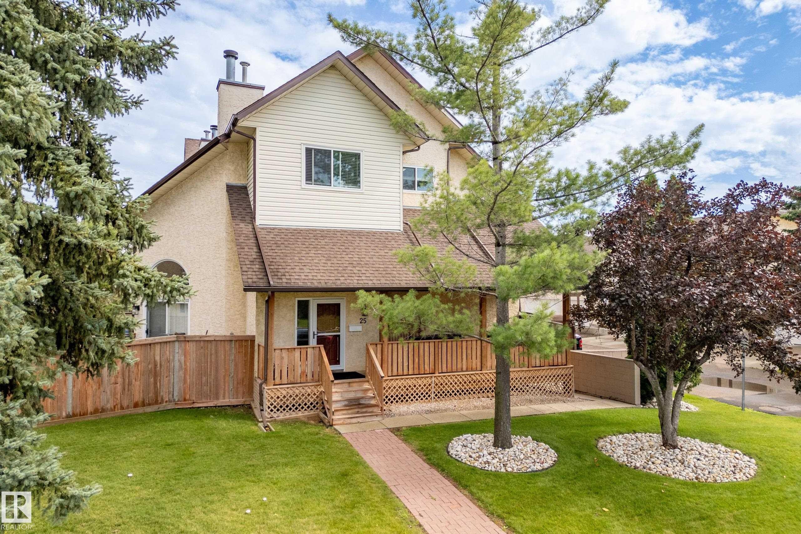 Two-story residence featuring stucco and siding exterior, a front deck with lattice detailing, and a brick paver walkway - #25 3811 85 St Nw, Edmonton, AB - Outdoor