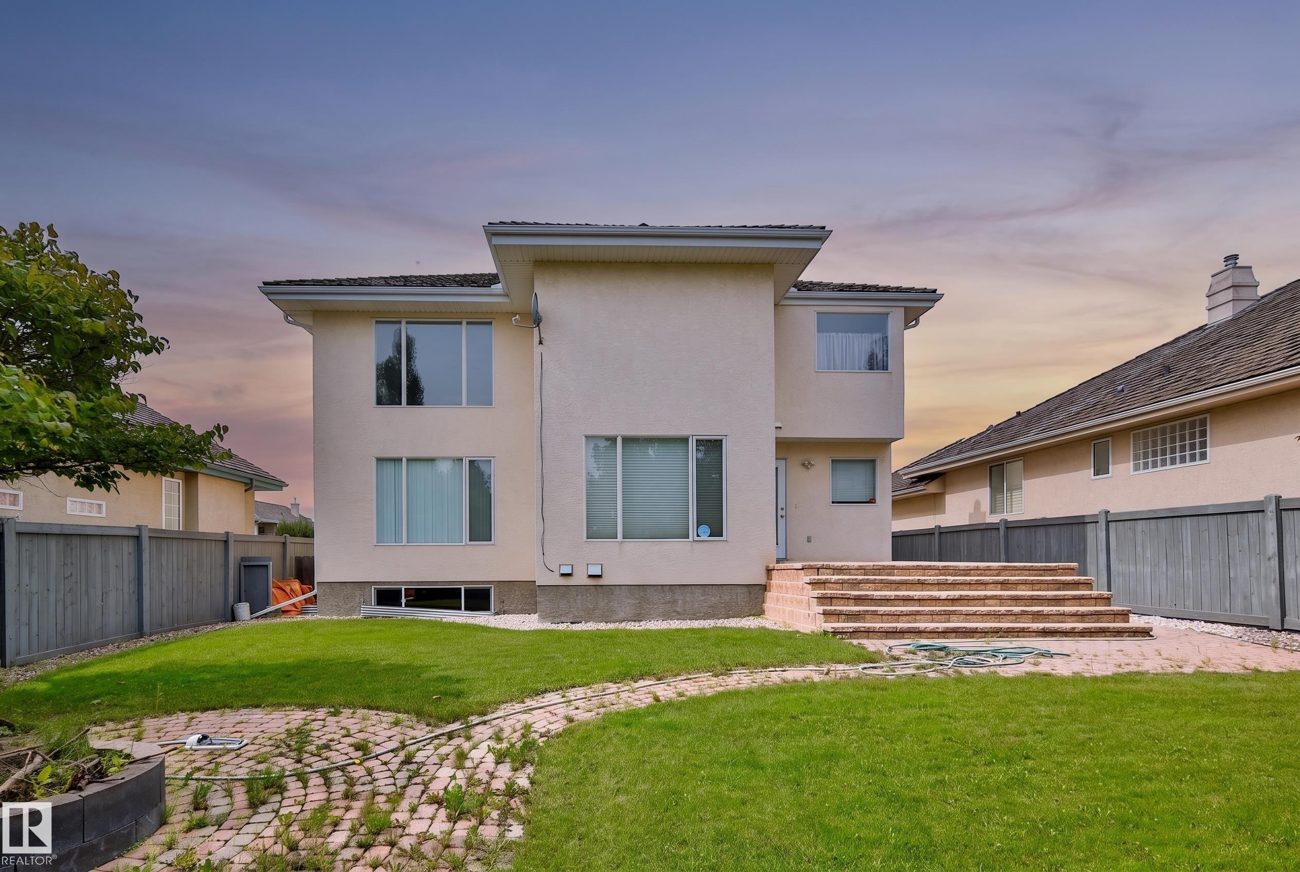 Rear exterior featuring multiple windows, brick steps, and a fenced perimeter - 237 Darlington Crescent Nw, Edmonton, AB - Outdoor