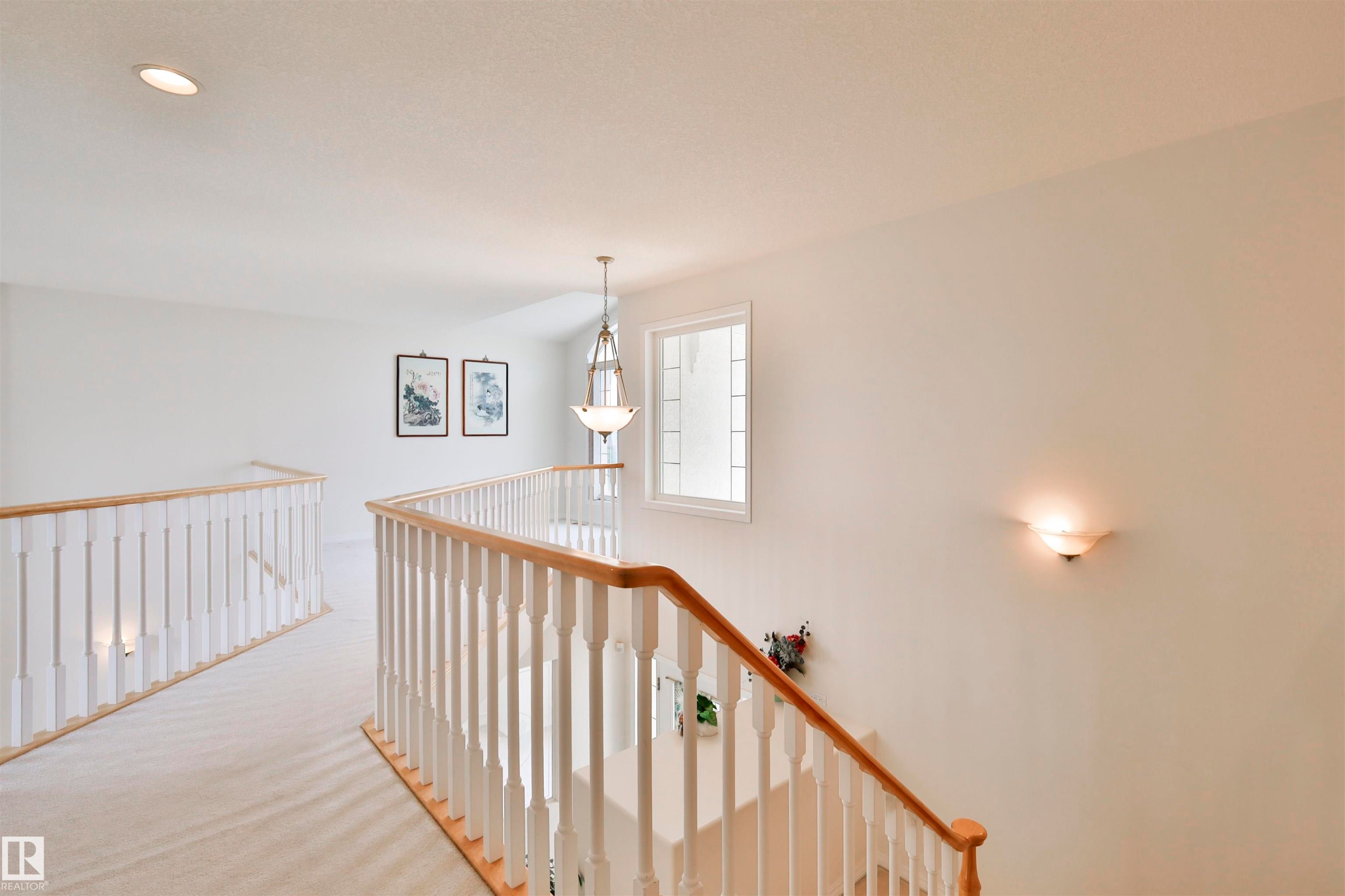 Carpeted upper hallway featuring a wood and white spindle railing, recessed ceiling lighting, a pendant light fixture, and a window with divided lites - 237 Darlington Crescent Nw, Edmonton, AB - Indoor Photo Showing Other Room