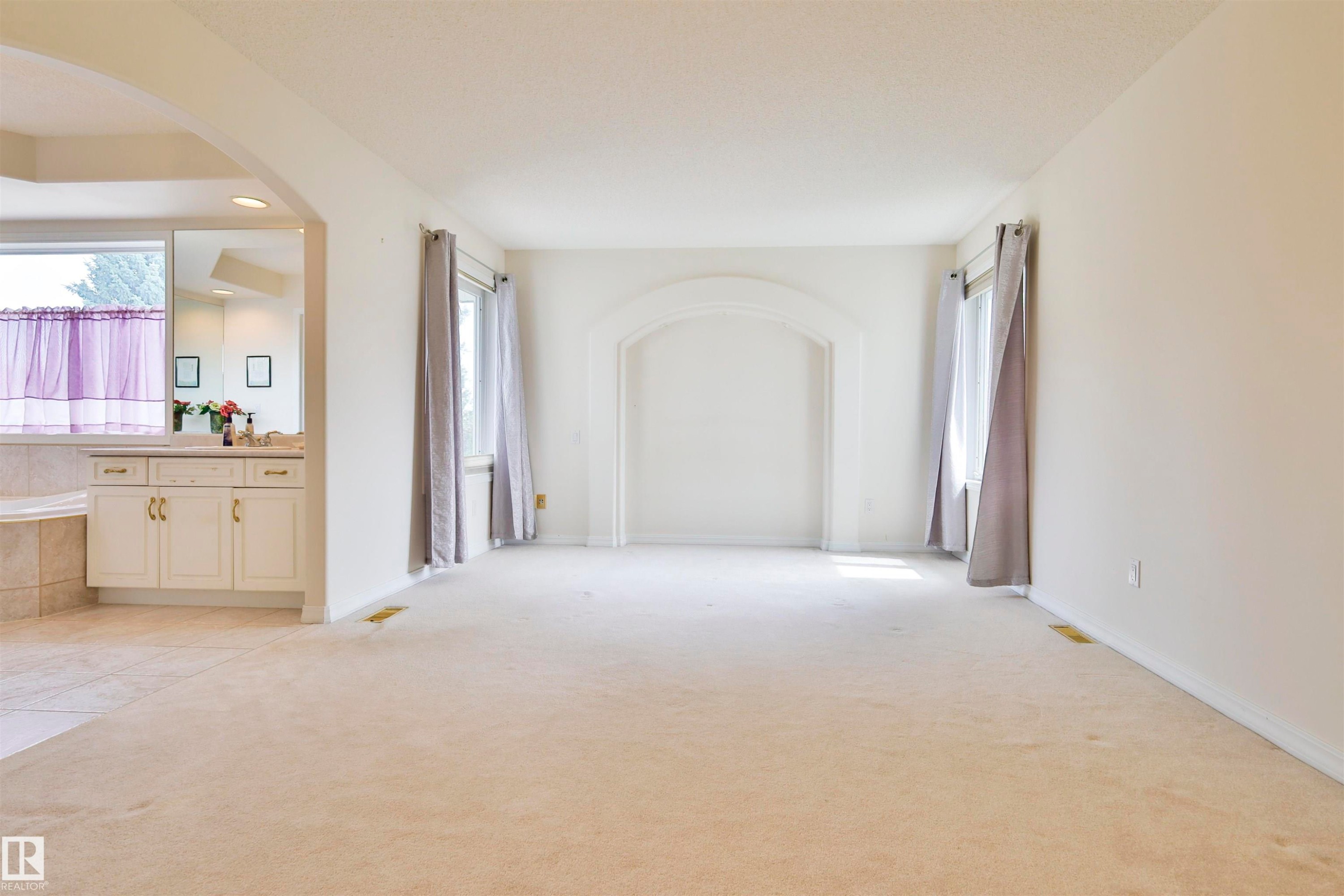 Carpeted flooring throughout, arched alcove, and multiple windows with drapery - 237 Darlington Crescent Nw, Edmonton, AB - Indoor Photo Showing Other Room