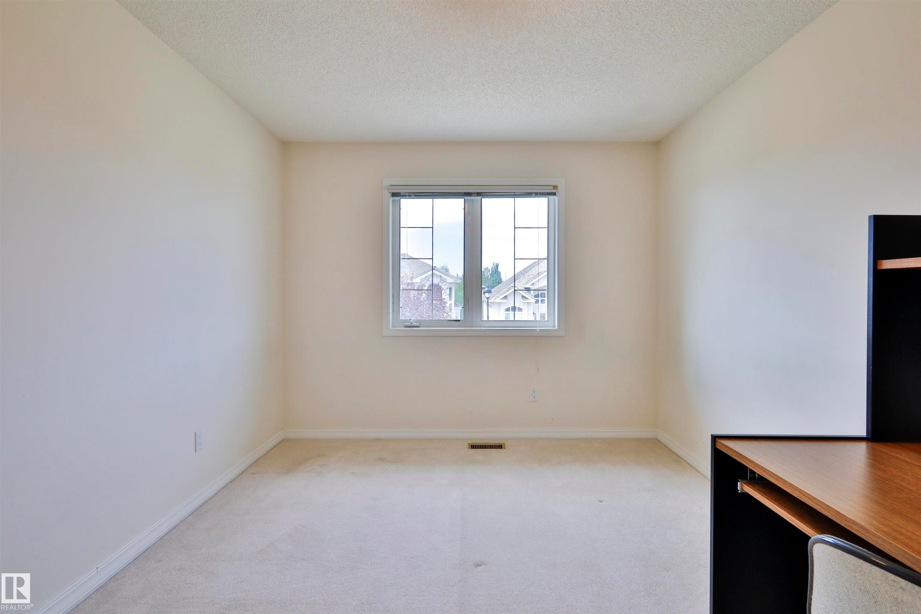 Single window with white trim, light-colored carpeting, and a built-in desk unit with wood-finish top and black shelving - 237 Darlington Crescent Nw, Edmonton, AB - Indoor Photo Showing Other Room