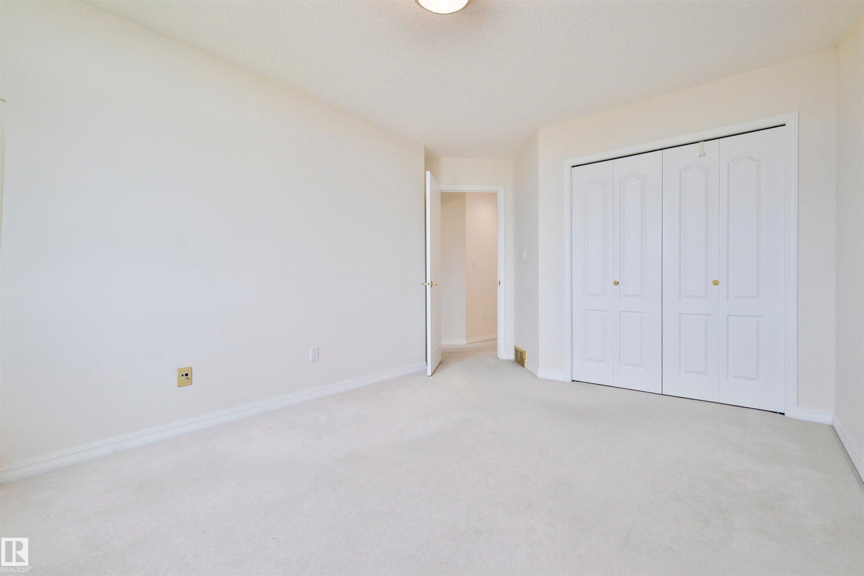 Carpeted flooring with light-toned walls, featuring a ceiling-mounted light fixture and bi-fold closet doors - 237 Darlington Crescent Nw, Edmonton, AB - Indoor