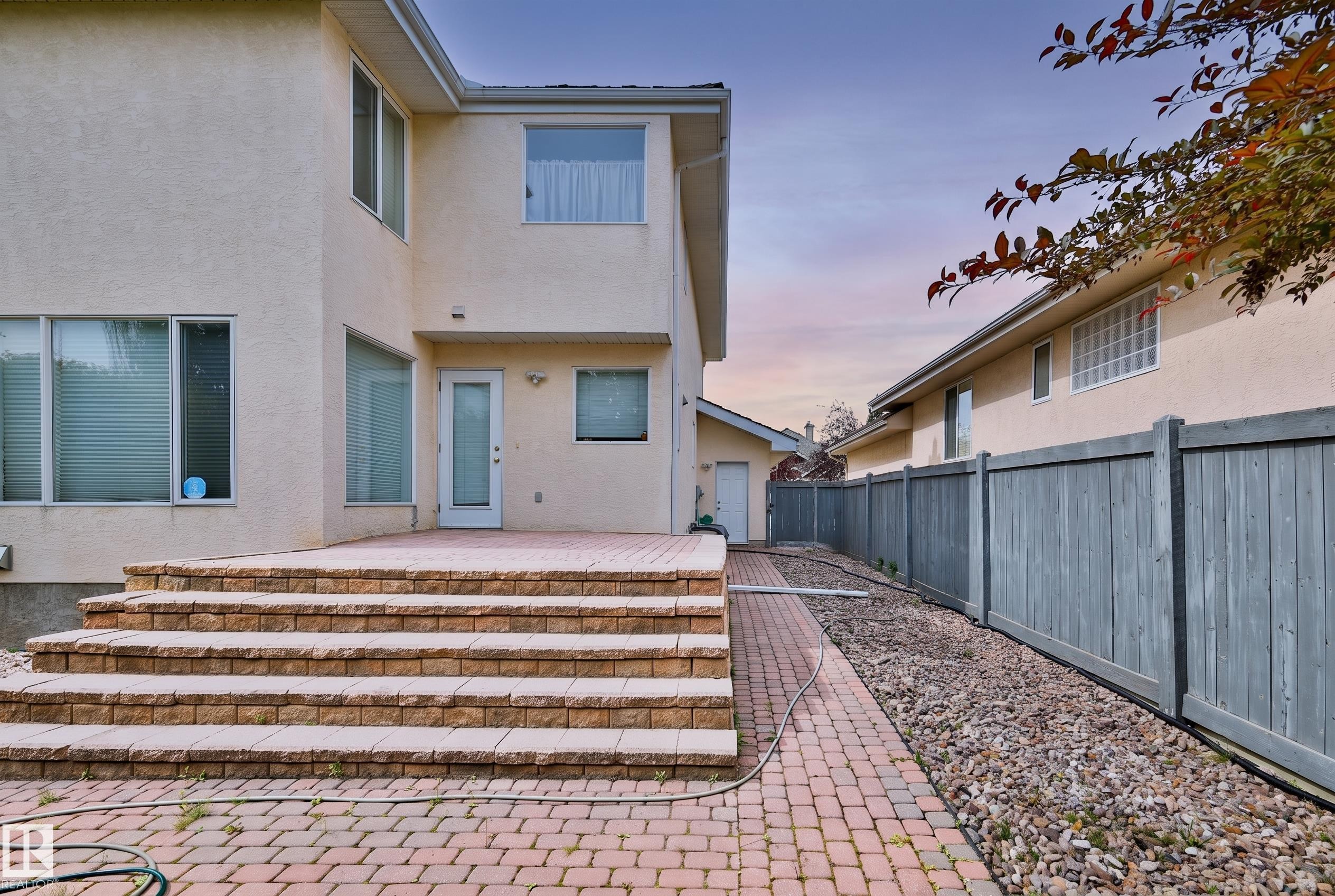 Exterior stucco finish, multi-level paver patio, paver walkway, wood fence, and upper-level windows - 237 Darlington Crescent Nw, Edmonton, AB - Outdoor
