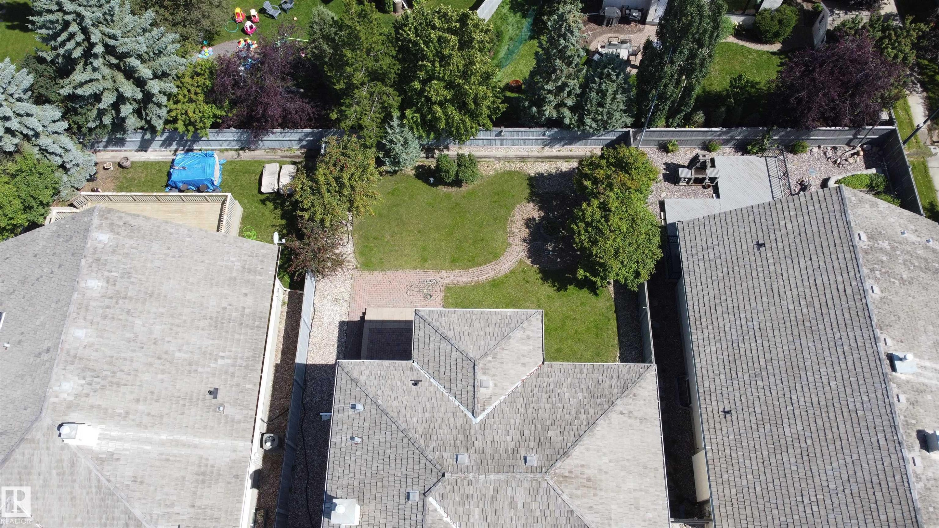 Expansive backyard featuring a manicured lawn, mature trees, and a hardscaped patio area - 237 Darlington Crescent Nw, Edmonton, AB - Outdoor