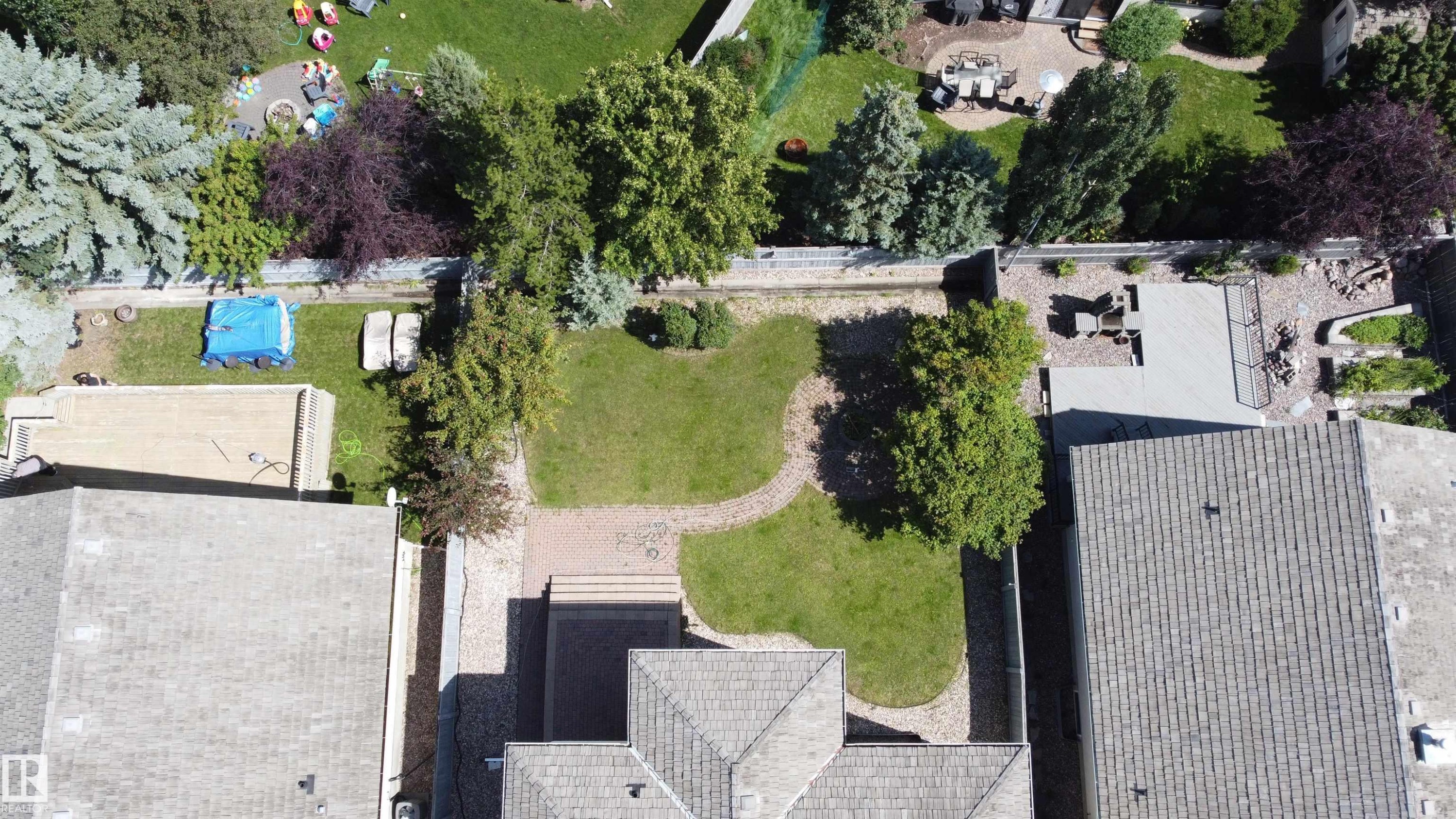 Expansive backyard with a manicured lawn, established trees, and a decorative pathway - 237 Darlington Crescent Nw, Edmonton, AB - Outdoor