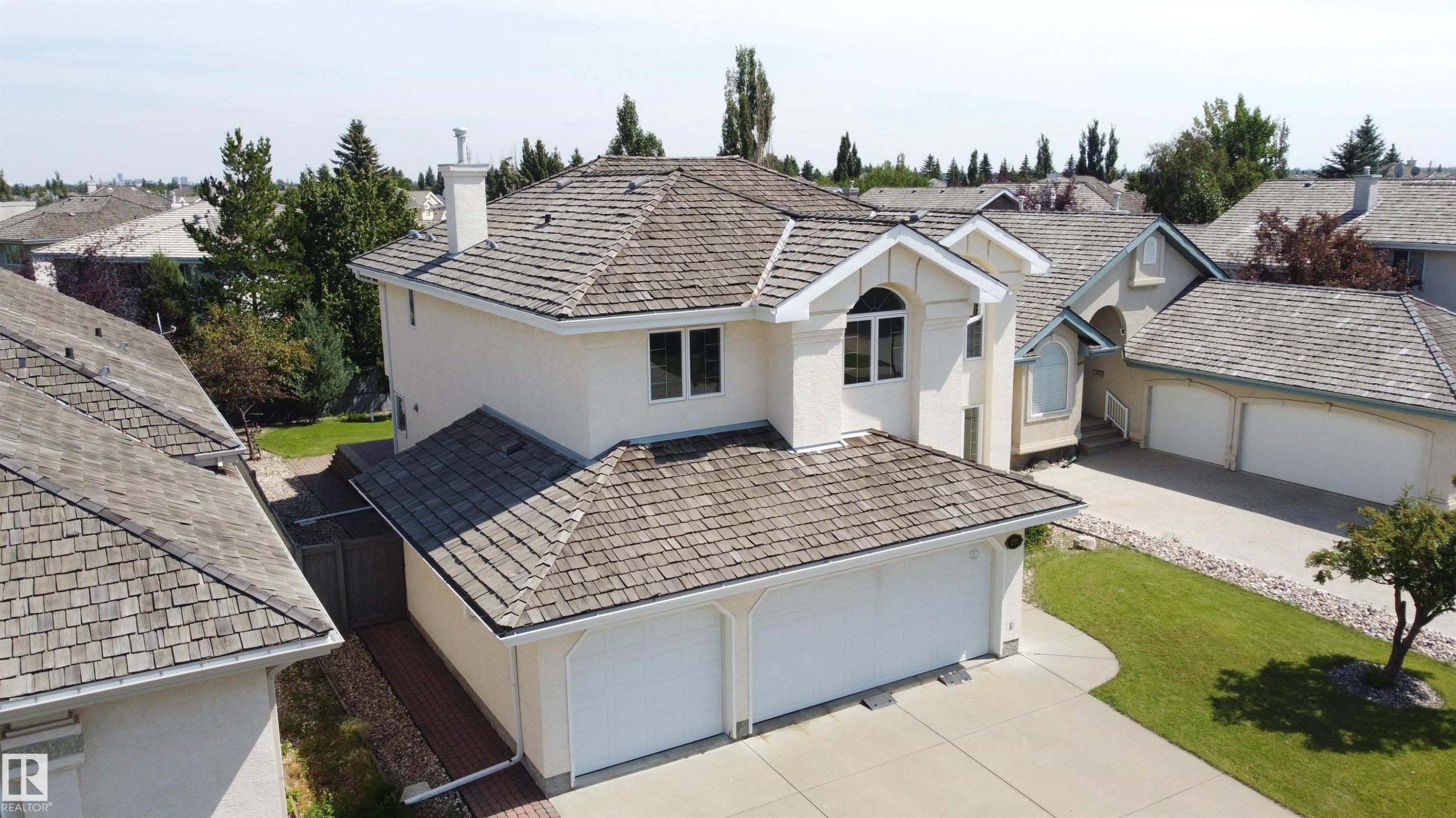 Two-story stucco exterior with wood-shingle roofing, arched window details, and an attached two-car garage - 237 Darlington Crescent Nw, Edmonton, AB - Outdoor