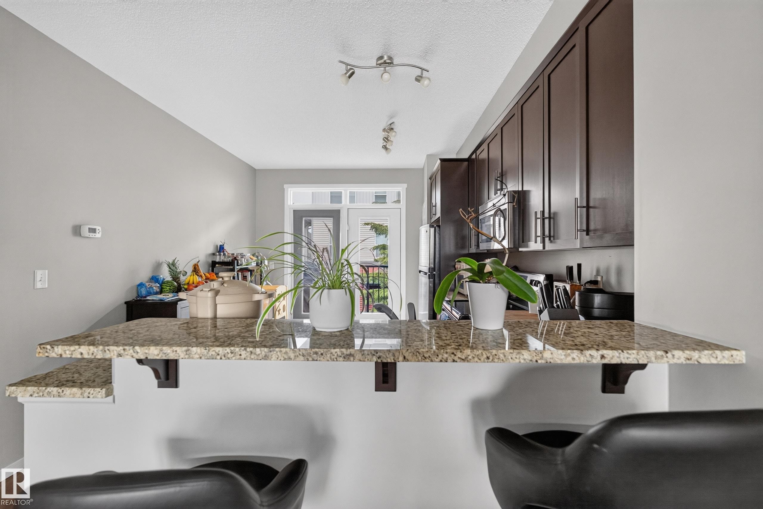 Kitchen breakfast bar featuring a granite countertop with integrated shelving - #53 603 Watt Bv Sw, Edmonton, AB - Indoor Photo Showing Kitchen With Upgraded Kitchen
