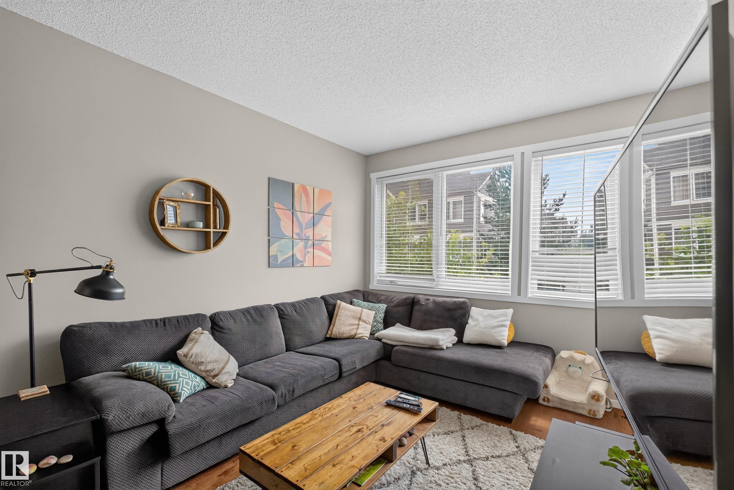 Living area featuring light gray walls and wood-finish flooring - #53 603 Watt Bv Sw, Edmonton, AB - Indoor Photo Showing Living Room