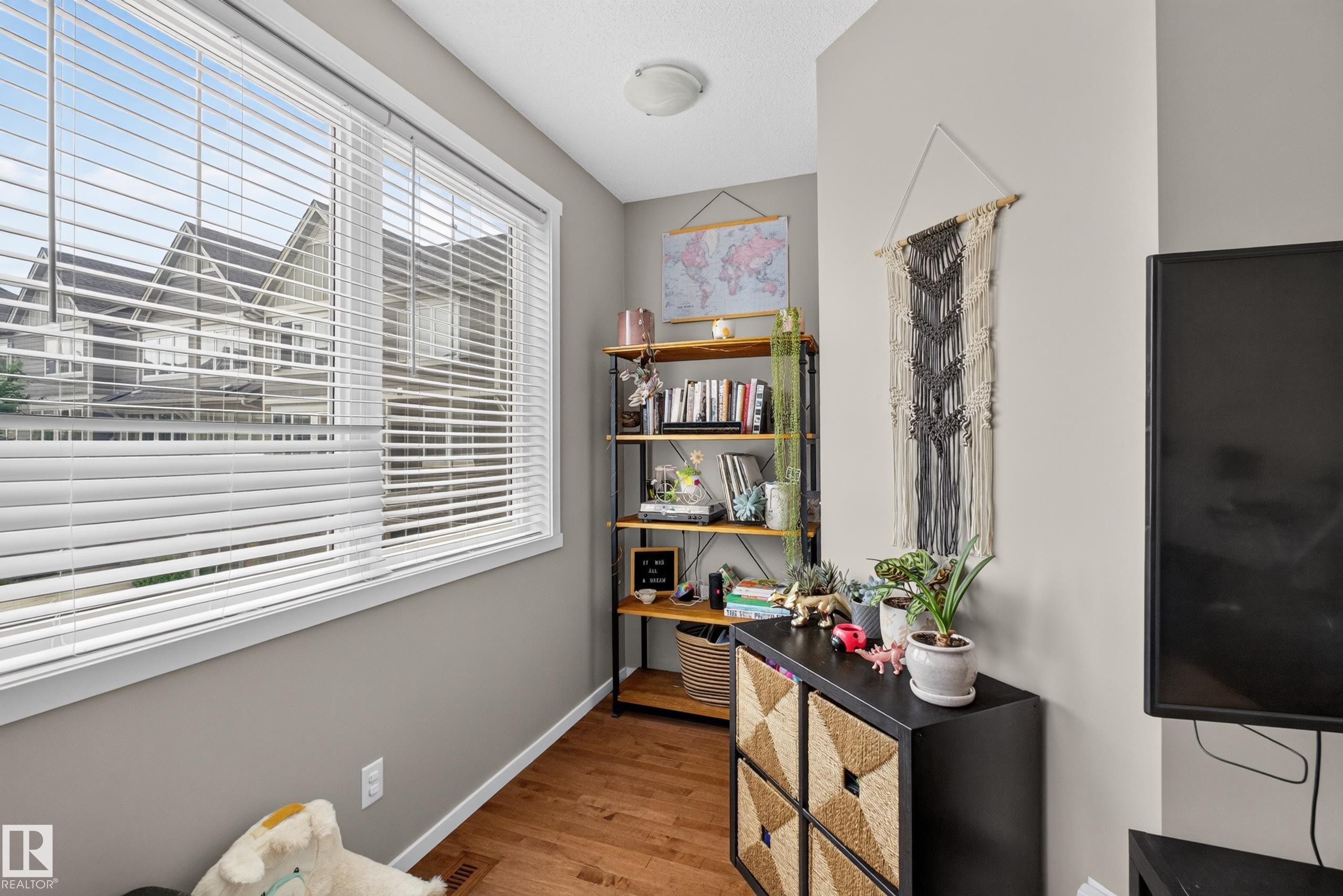 Hardwood-style flooring throughout this room with neutral wall tones - #53 603 Watt Bv Sw, Edmonton, AB - Indoor Photo Showing Other Room