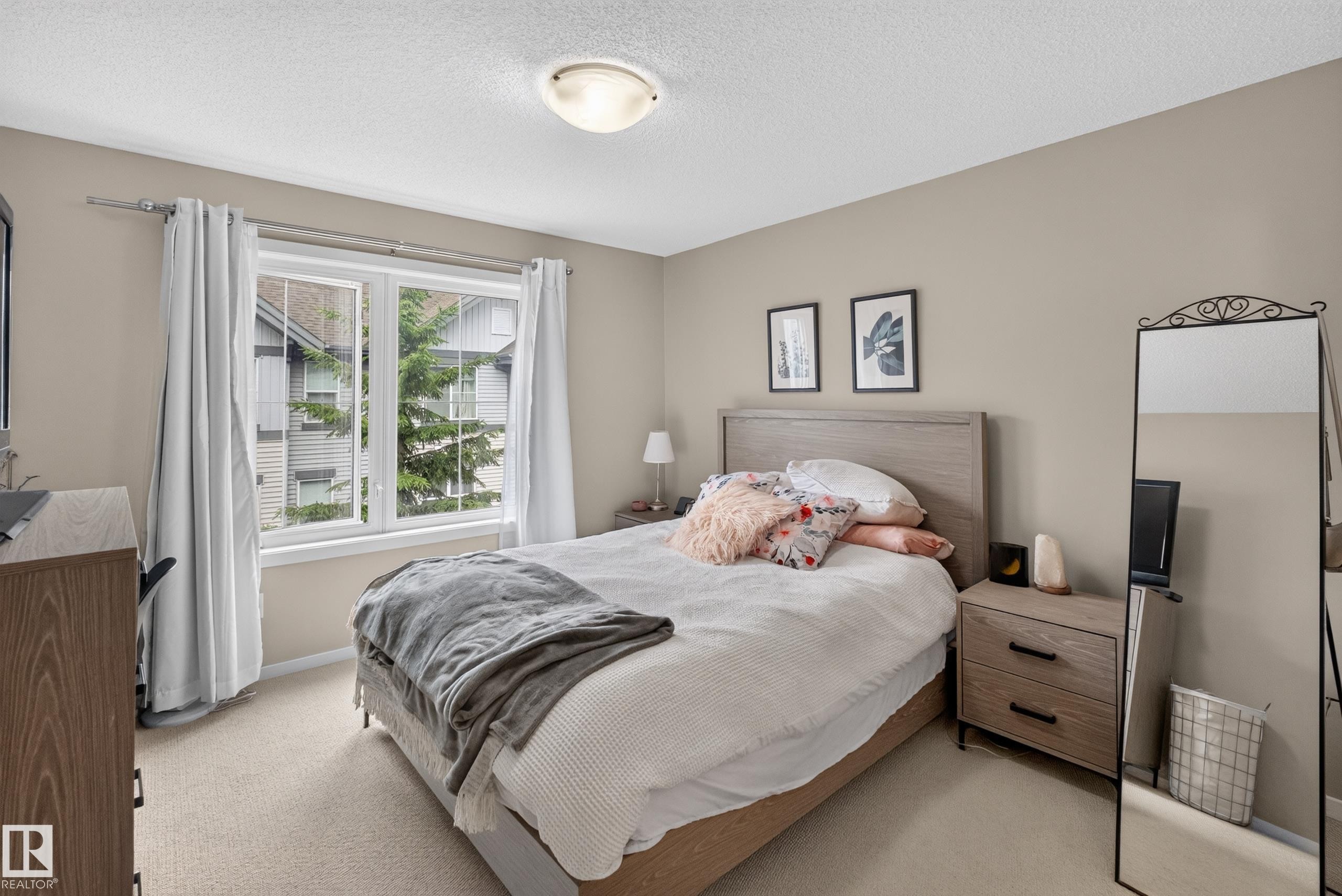 Bedroom featuring a double window with white trim, neutral carpet flooring, and a flush mount ceiling light fixture - #53 603 Watt Bv Sw, Edmonton, AB - Indoor Photo Showing Bedroom
