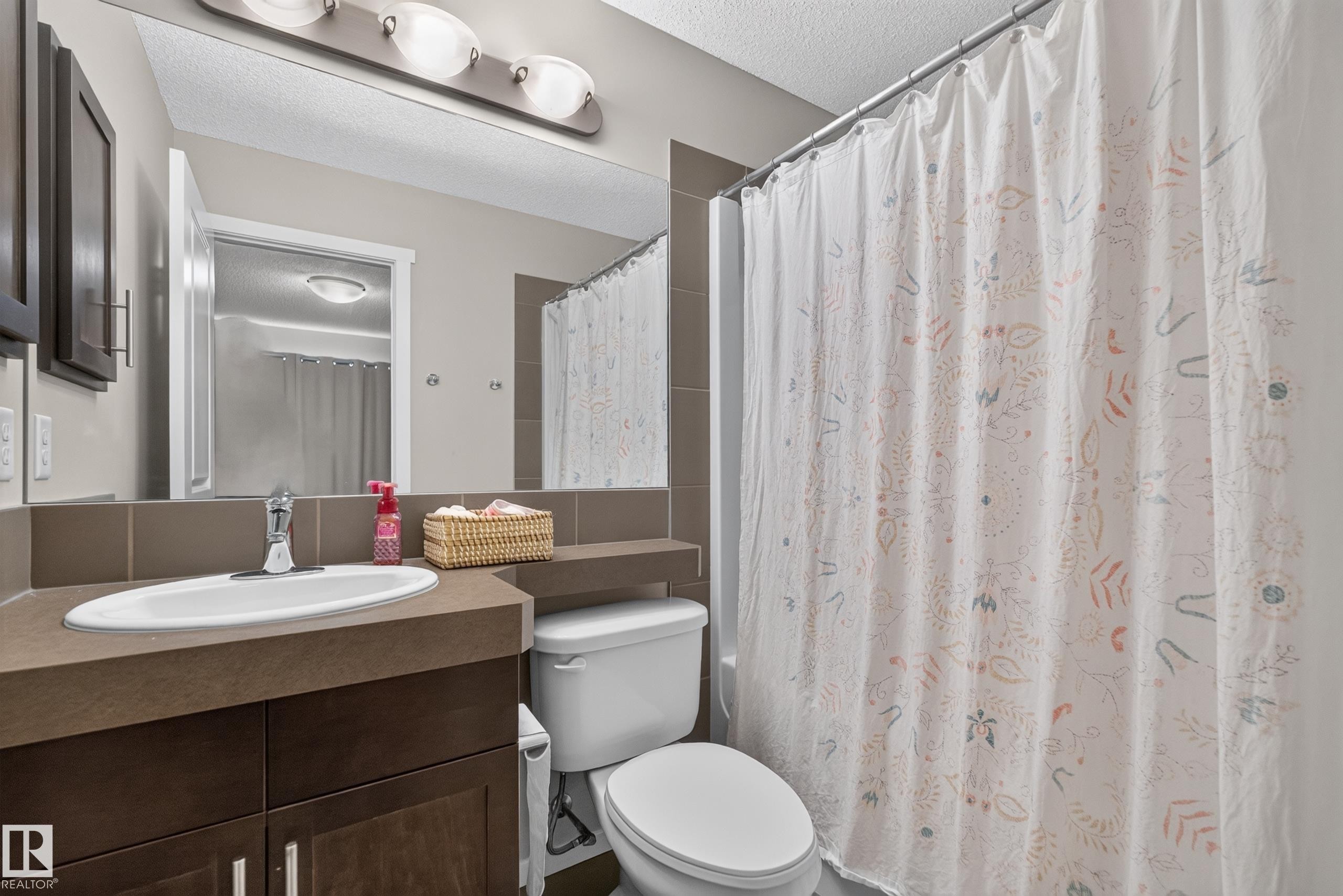 Bathroom featuring a built-in vanity with an integrated sink, dark wood-finish cabinetry, and a full-width mirror - #53 603 Watt Bv Sw, Edmonton, AB - Indoor Photo Showing Bathroom