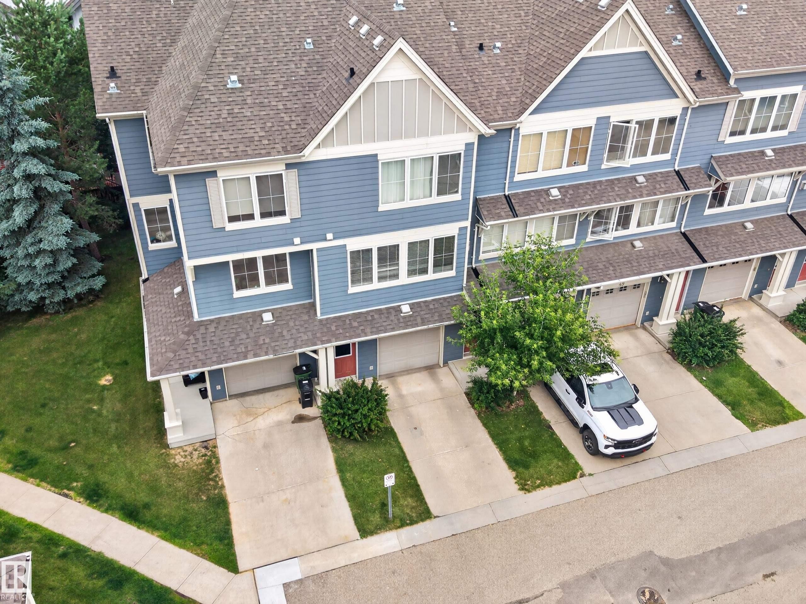 Multi-level townhome featuring blue siding, white trim, and a shingled roof - #53 603 Watt Bv Sw, Edmonton, AB - Outdoor With Facade