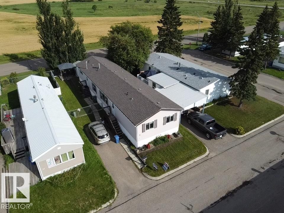 Rooftop with asphalt shingles and metal roofing, mature evergreen trees, paved driveway, and grassed areas - #56 4202 45 St, Wetaskiwin, AB - Outdoor With View