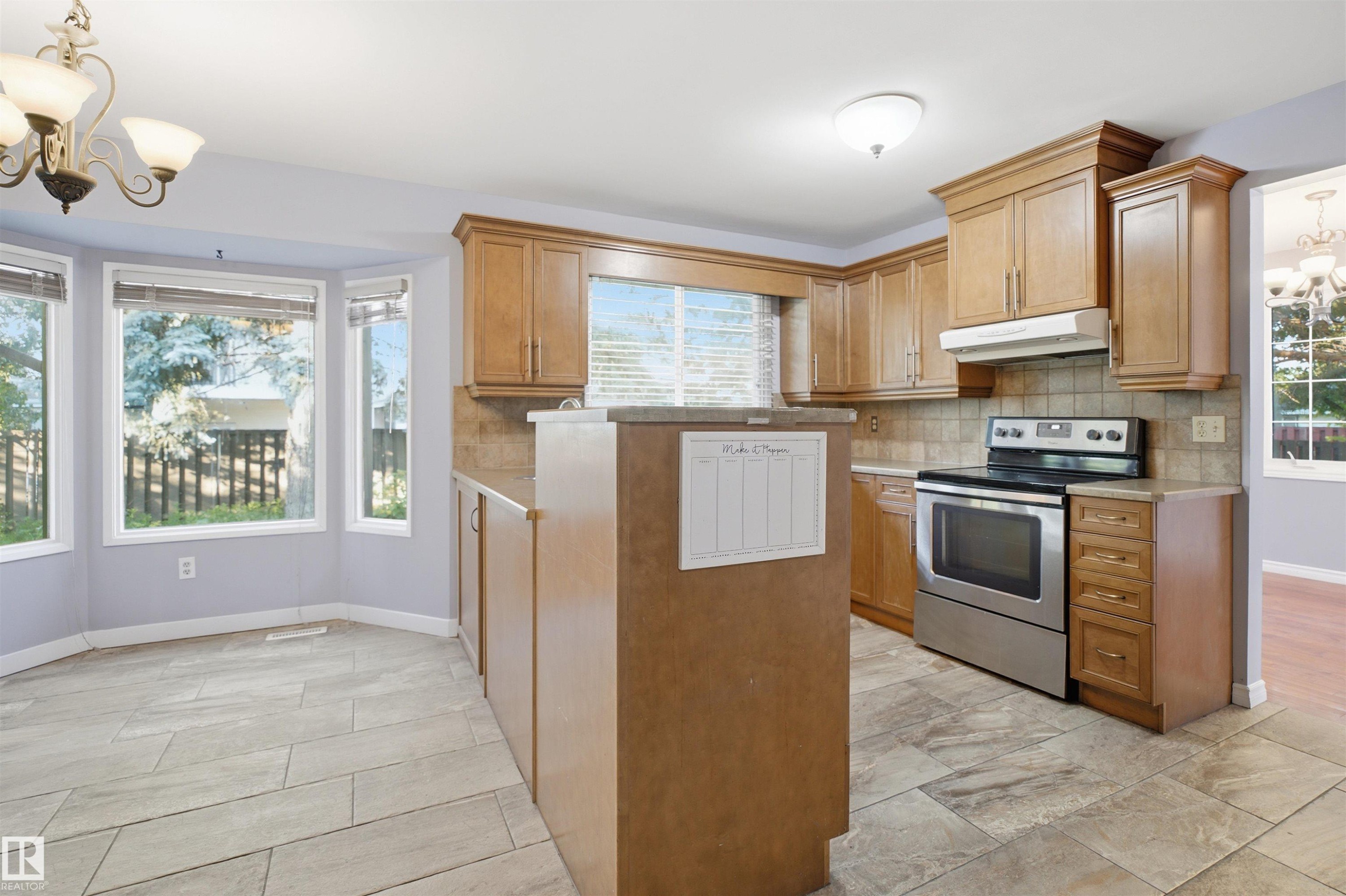 Kitchen featuring wood cabinetry, stainless steel range, tiled backsplash, and tile flooring - 3432 Hill View Crescent Nw, Edmonton, AB - Indoor Photo Showing Kitchen