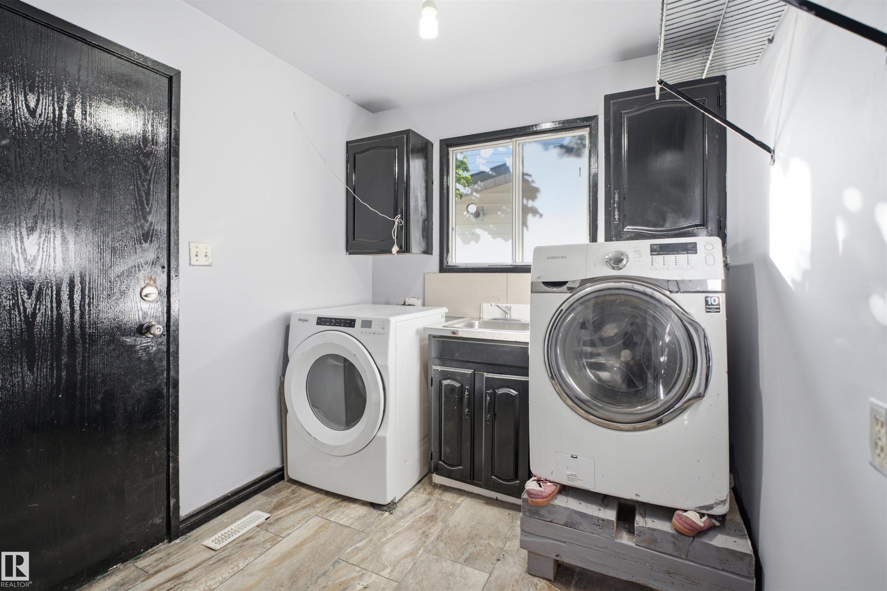 Laundry area with wood-finish flooring, dark cabinetry, and a window - 3432 Hill View Crescent Nw, Edmonton, AB - Indoor Photo Showing Laundry Room