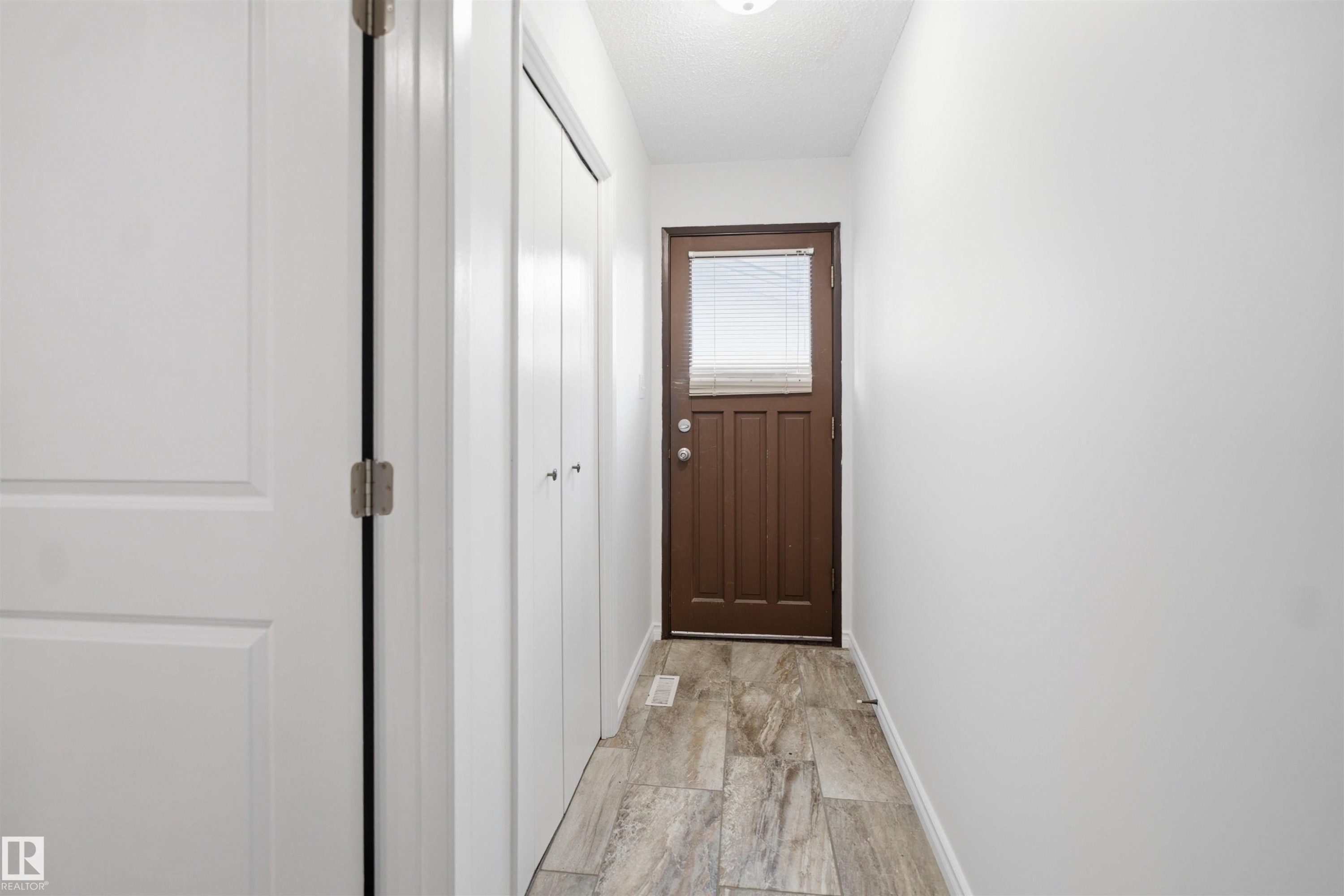 Wood-finish flooring, white walls, and a brown door with an upper window - 3432 Hill View Crescent Nw, Edmonton, AB - Indoor Photo Showing Other Room