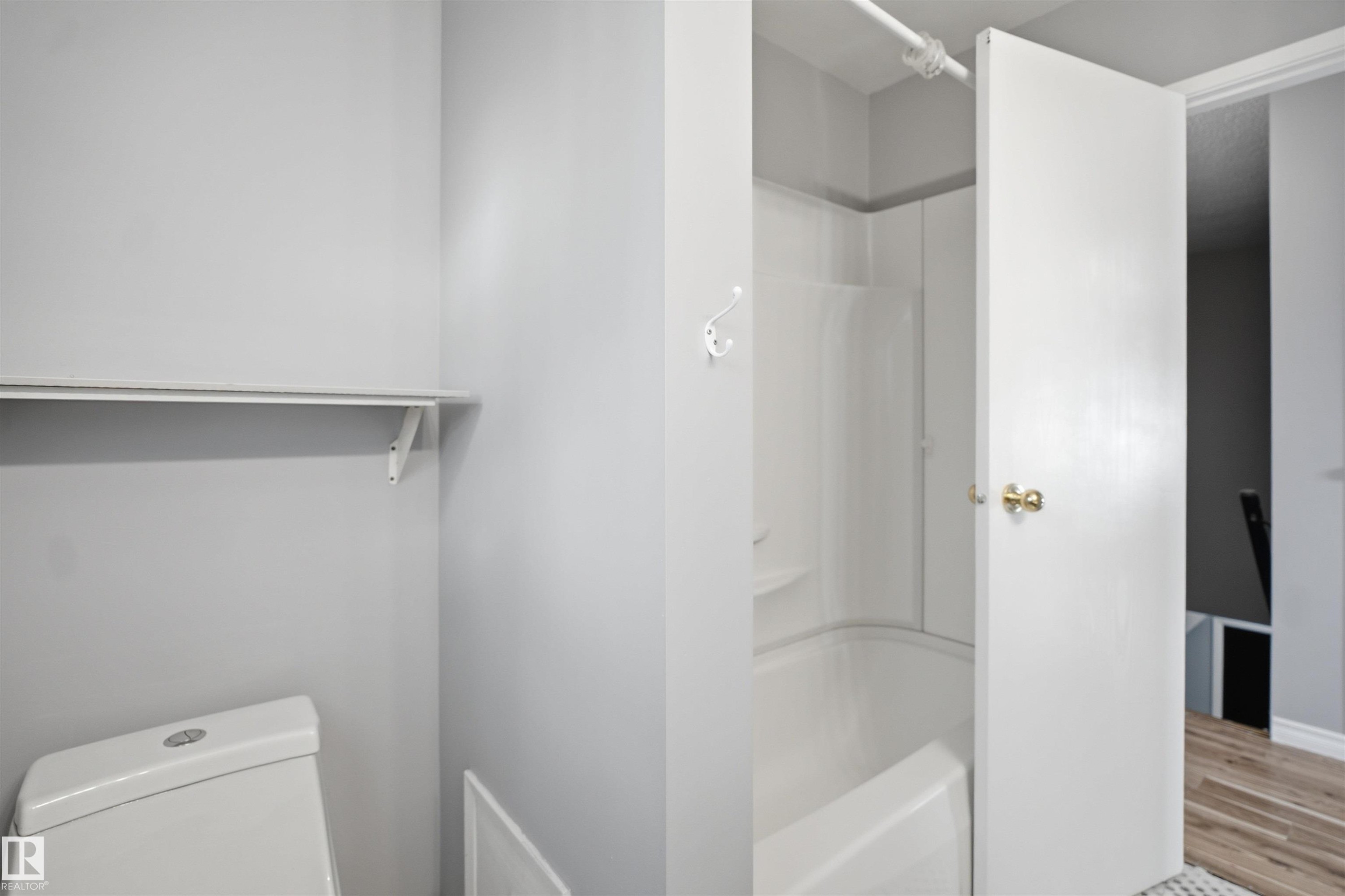 White bathtub with a shower surround and wall-mounted hook - 3432 Hill View Crescent Nw, Edmonton, AB - Indoor