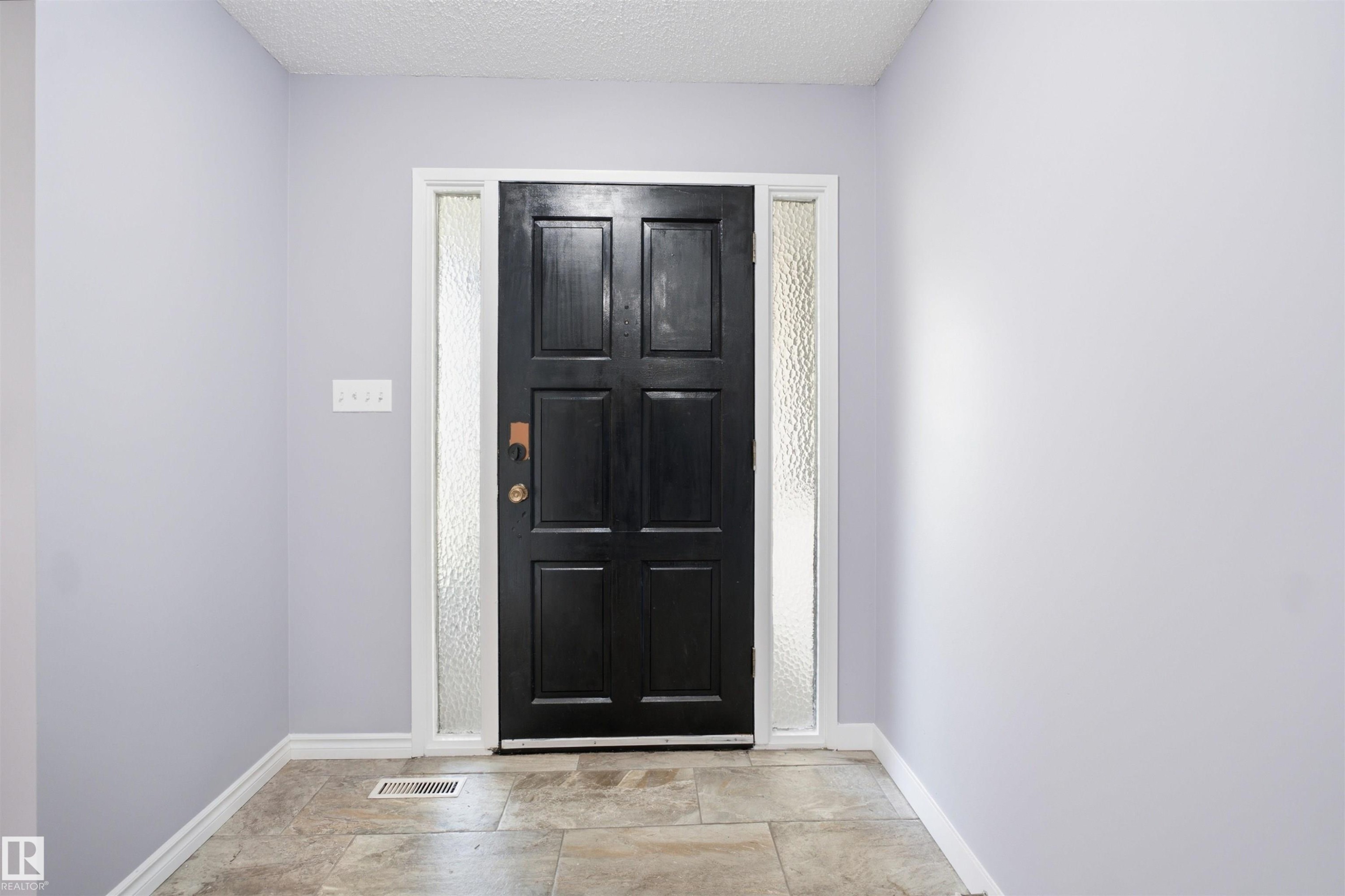 Front entry with a paneled door, textured glass sidelights, and tile flooring - 3432 Hill View Crescent Nw, Edmonton, AB - Indoor Photo Showing Other Room