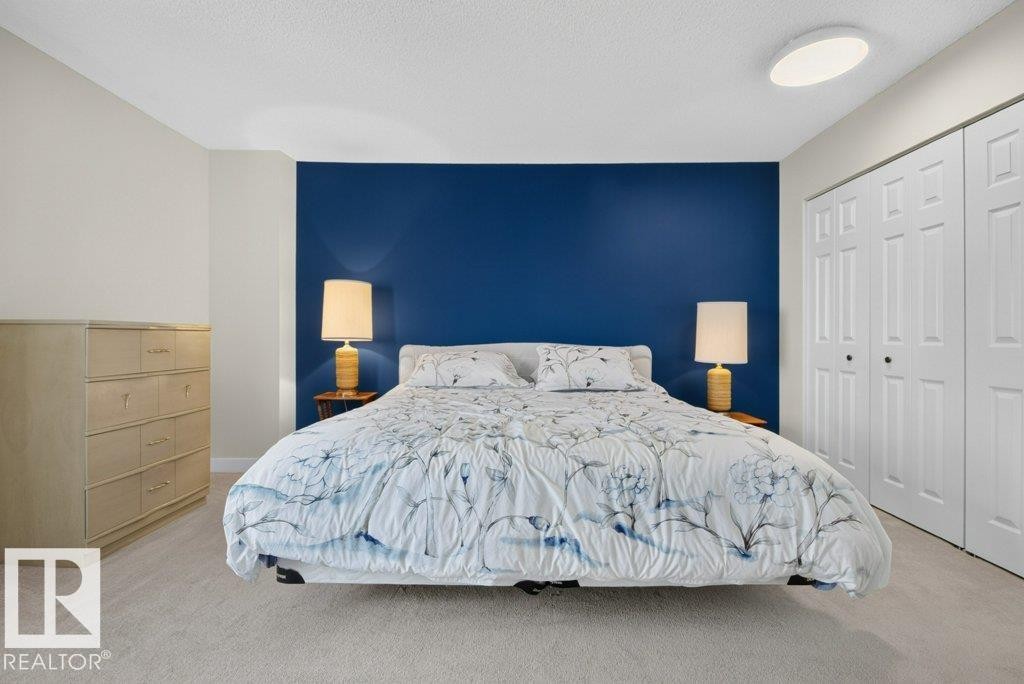 Bedroom featuring a bold accent wall, neutral carpeting, and a flush-mount ceiling light - #804 11027 87 Av Nw, Edmonton, AB - Indoor Photo Showing Bedroom