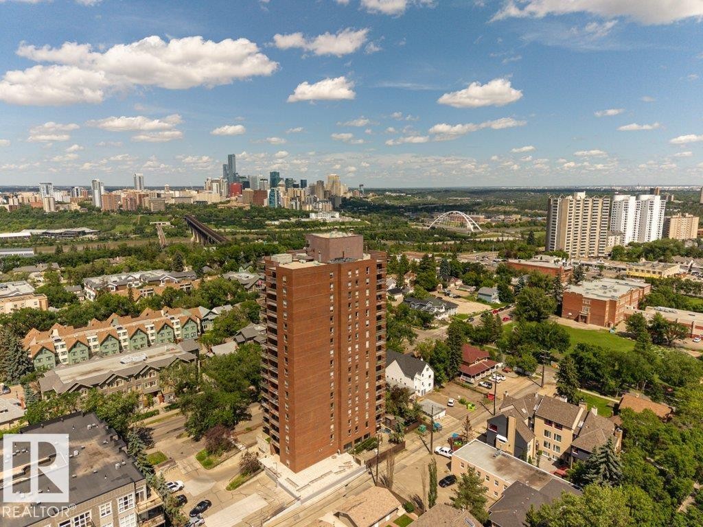 Brick high-rise building surrounded by urban landscaping, featuring multiple balconies and a large rooftop structure - #804 11027 87 Av Nw, Edmonton, AB - Outdoor With View