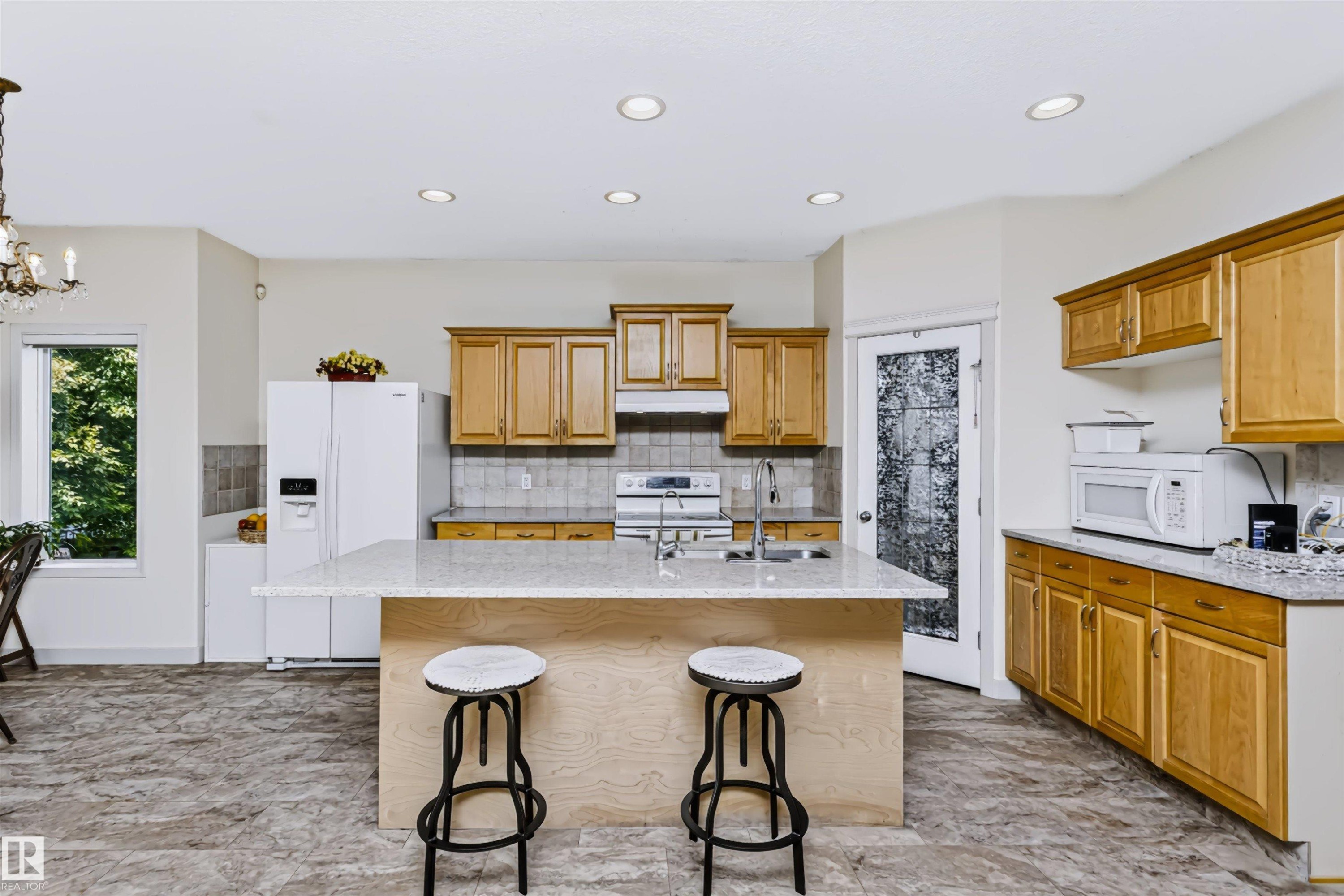 Kitchen featuring a large island with countertop seating, recessed lighting, wood cabinetry, and tiled flooring - 1720 Robertson Place Sw, Edmonton, AB - Indoor Photo Showing Kitchen