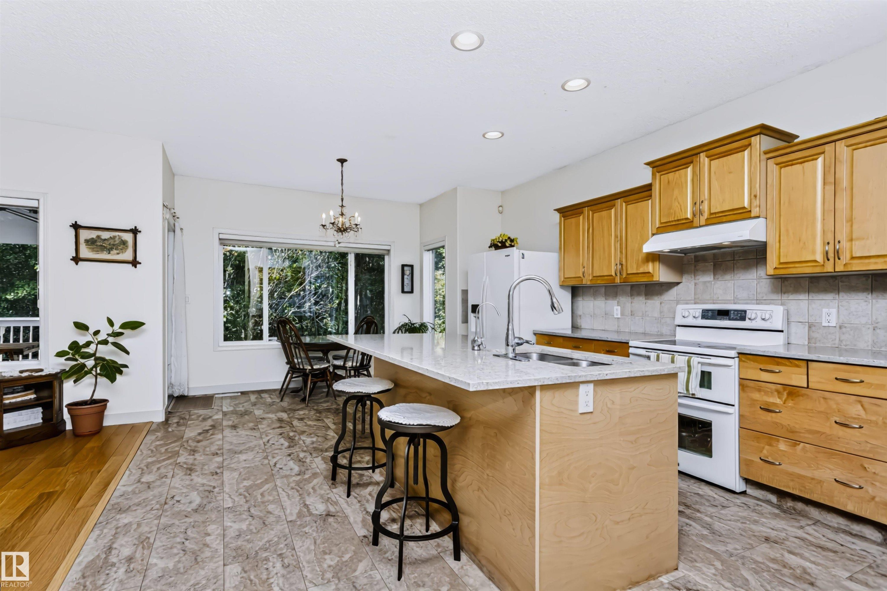 Kitchen featuring wood-finish cabinetry, light-toned countertops, a stainless steel sink, and recessed lighting - 1720 Robertson Place Sw, Edmonton, AB - Indoor Photo Showing Kitchen With Double Sink