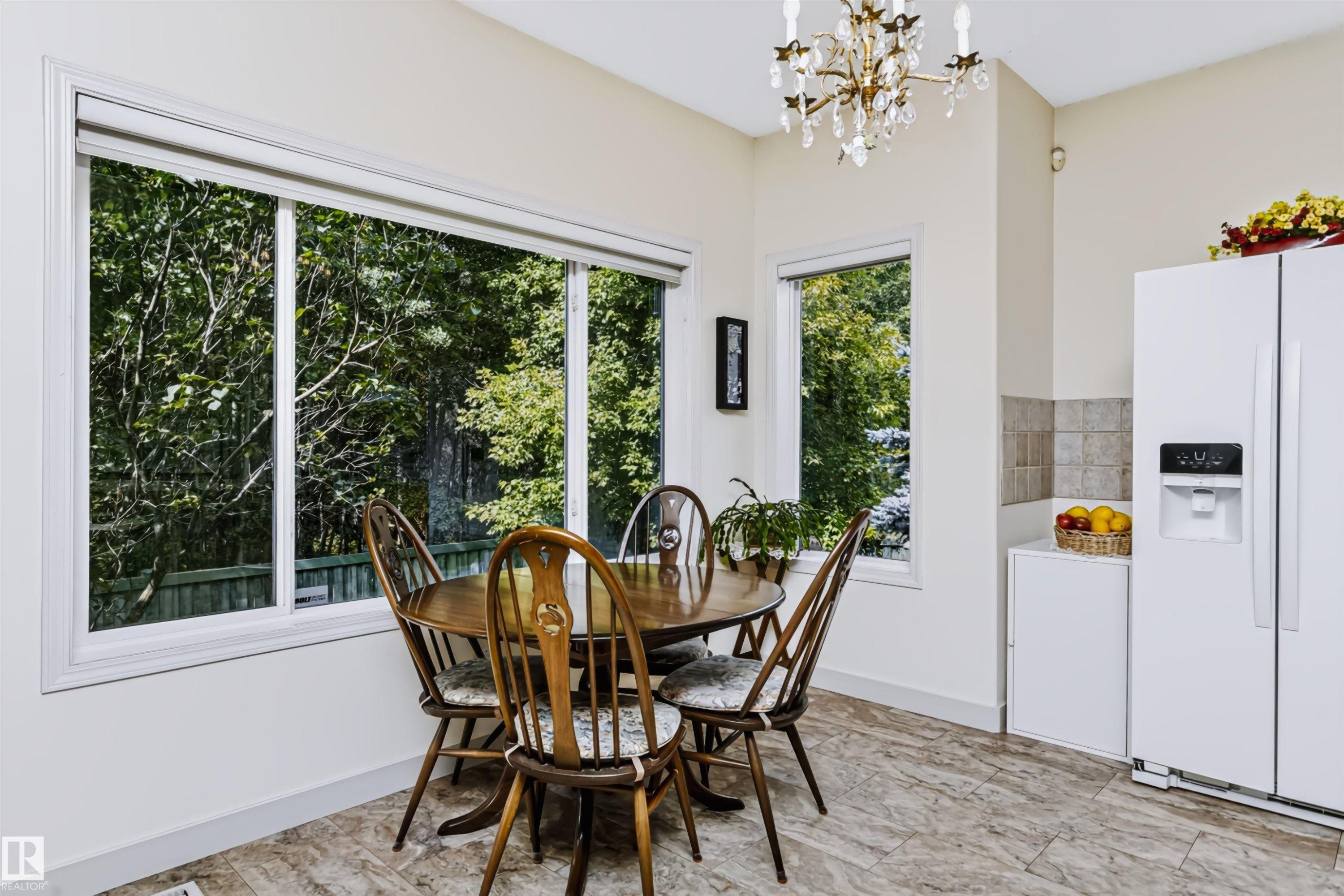 Expansive window with white trim, light-colored tile flooring, and a chandelier lighting fixture - 1720 Robertson Place Sw, Edmonton, AB - Indoor Photo Showing Dining Room