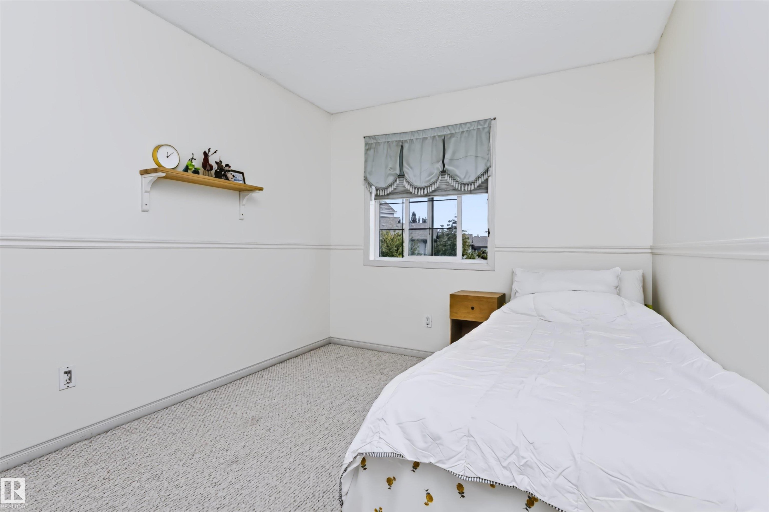 Wall-to-wall carpeting with light neutral walls, featuring a single window - 1720 Robertson Place Sw, Edmonton, AB - Indoor Photo Showing Bedroom