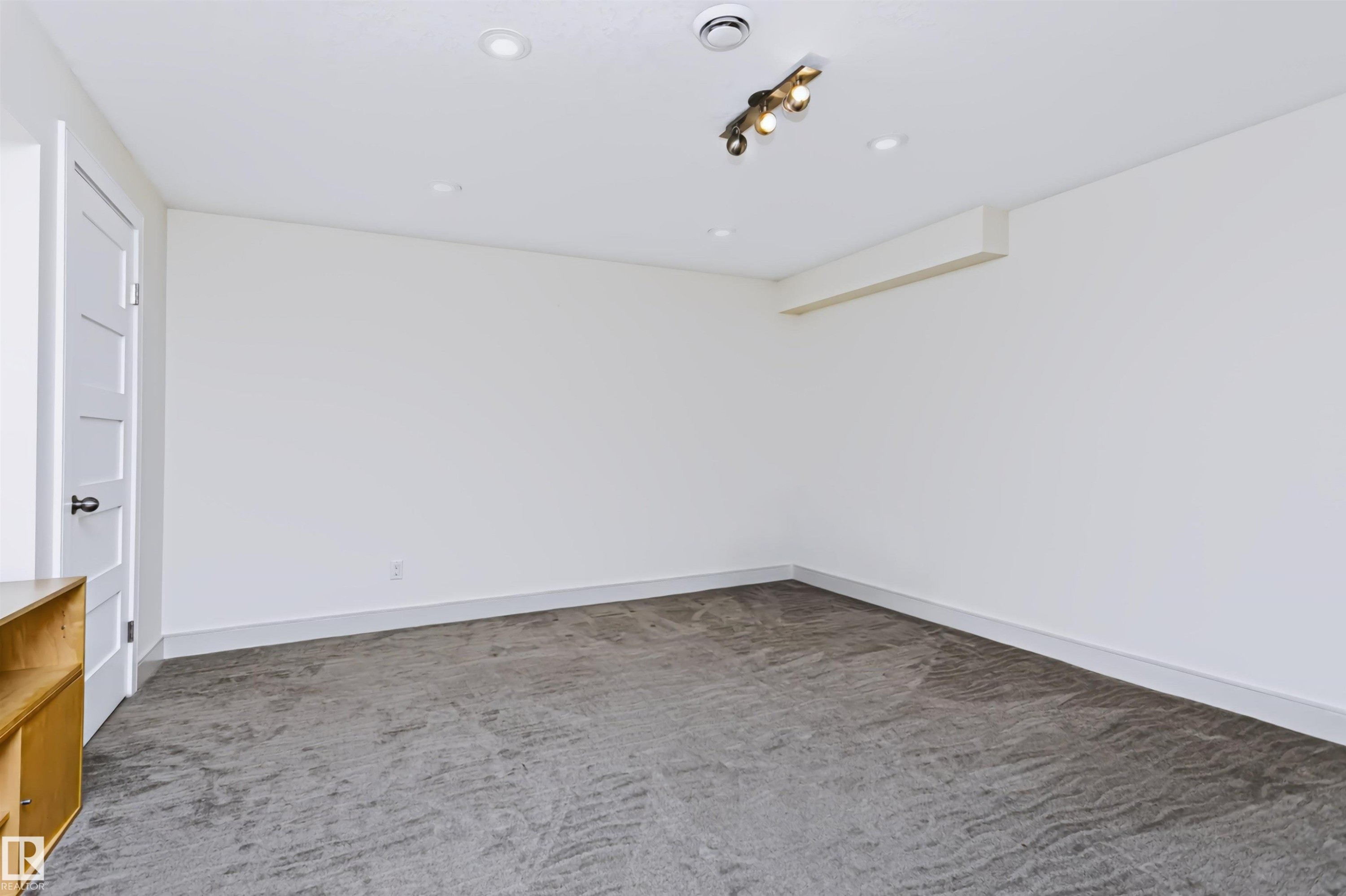 Recessed ceiling lighting, track lighting fixture, white interior door with contemporary hardware, light gray carpeting, and white wall finishes - 1720 Robertson Place Sw, Edmonton, AB - Indoor Photo Showing Other Room