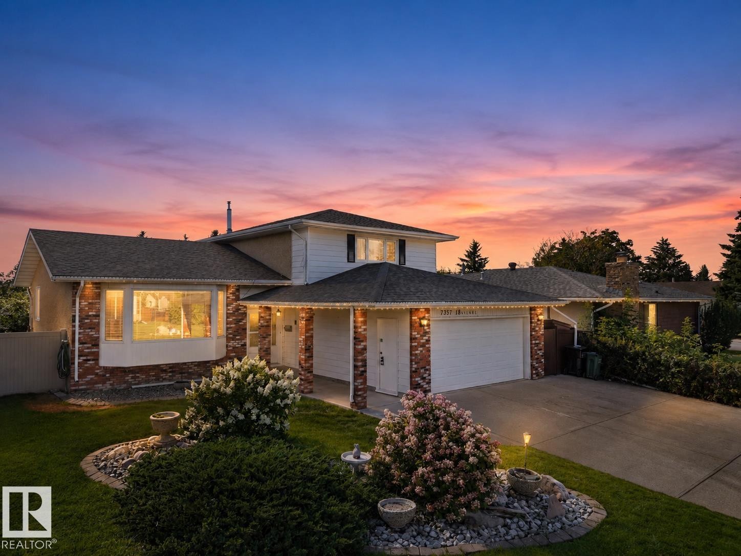Two-story residence featuring a brick facade with a bay window, attached garage, and a concrete driveway - 7357 18 Avenue Nw, Edmonton, AB - Outdoor