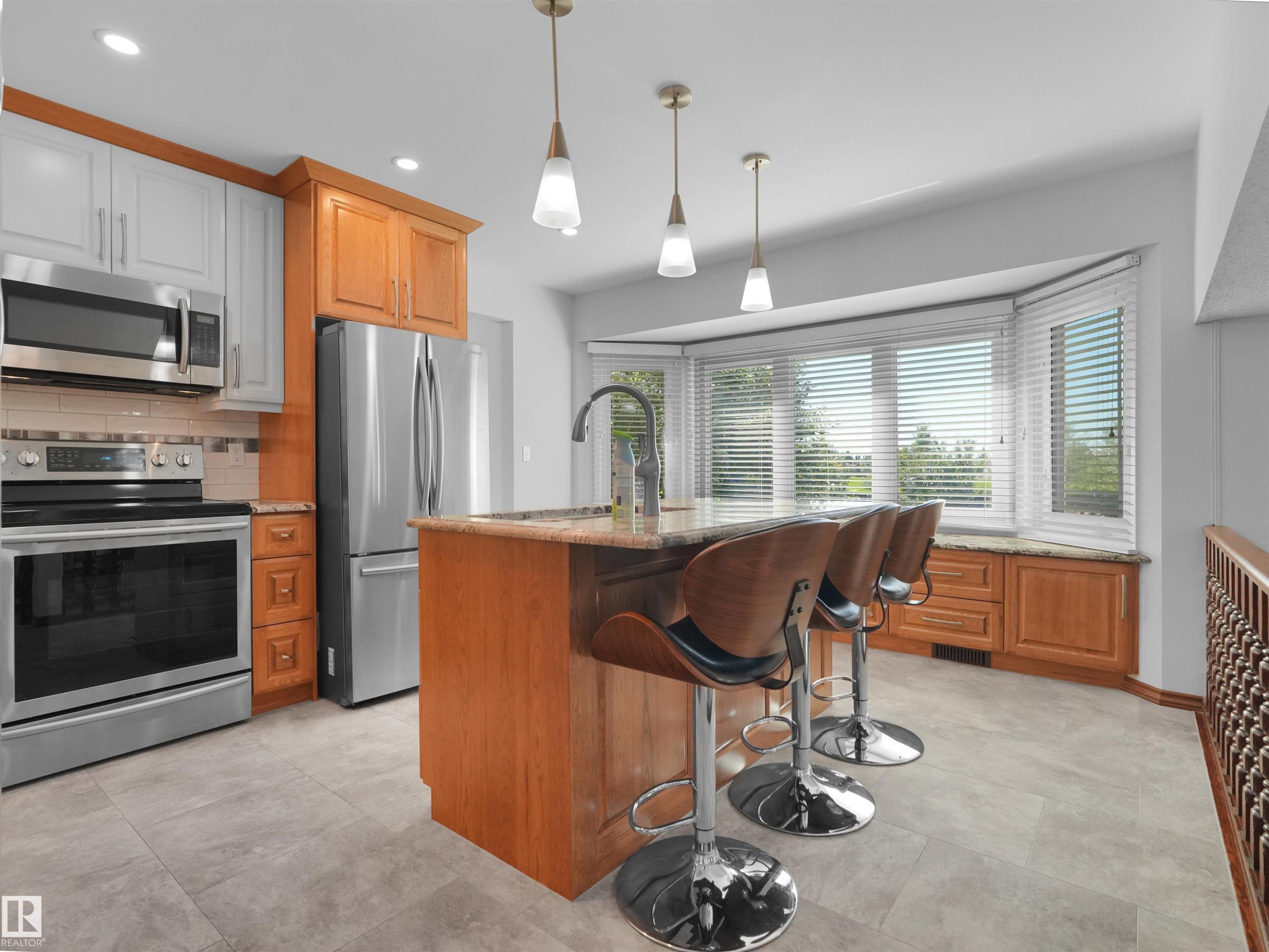 Kitchen featuring a bay window, stainless steel appliances, an island with seating, pendant lighting, and tile flooring - 7357 18 Avenue Nw, Edmonton, AB - Indoor Photo Showing Kitchen With Upgraded Kitchen