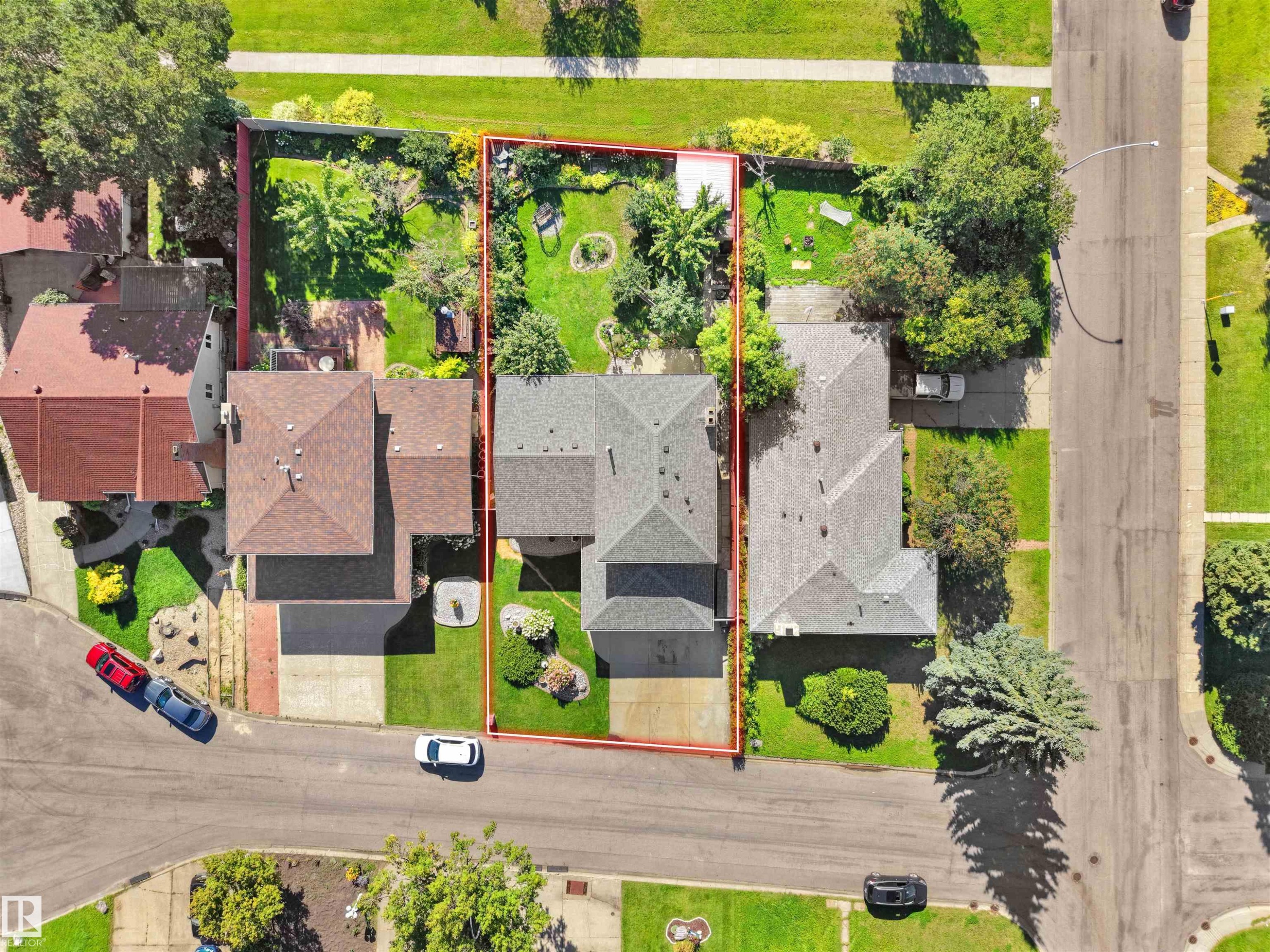 Gable roof with asphalt shingles, expansive green lawn, mature trees, concrete driveway, and paved street access - 7357 18 Avenue Nw, Edmonton, AB - Outdoor With View