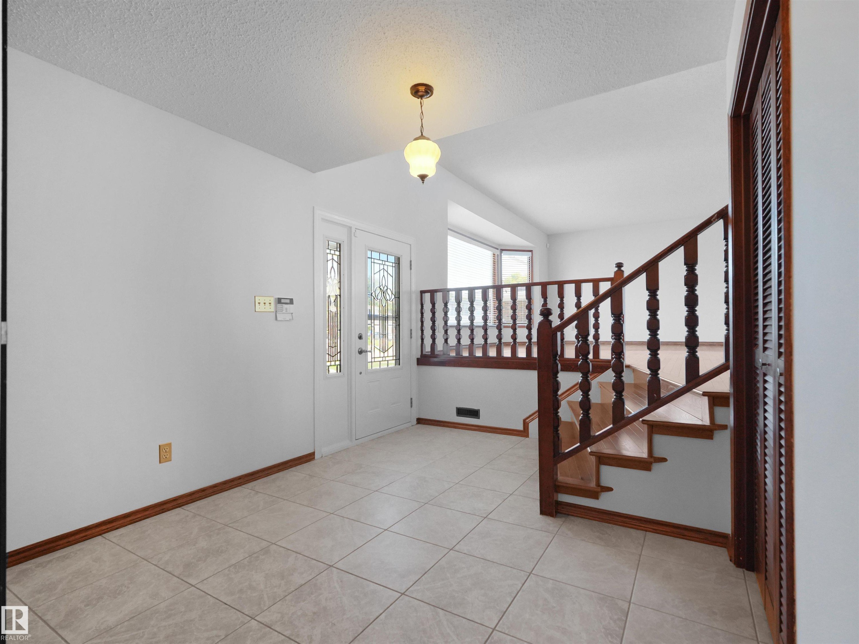 Welcoming foyer with tile flooring, ornamental wood stair railing with turned balusters, pendant lighting, and direct access to exterior entry - 7357 18 Avenue Nw, Edmonton, AB - Indoor Photo Showing Other Room
