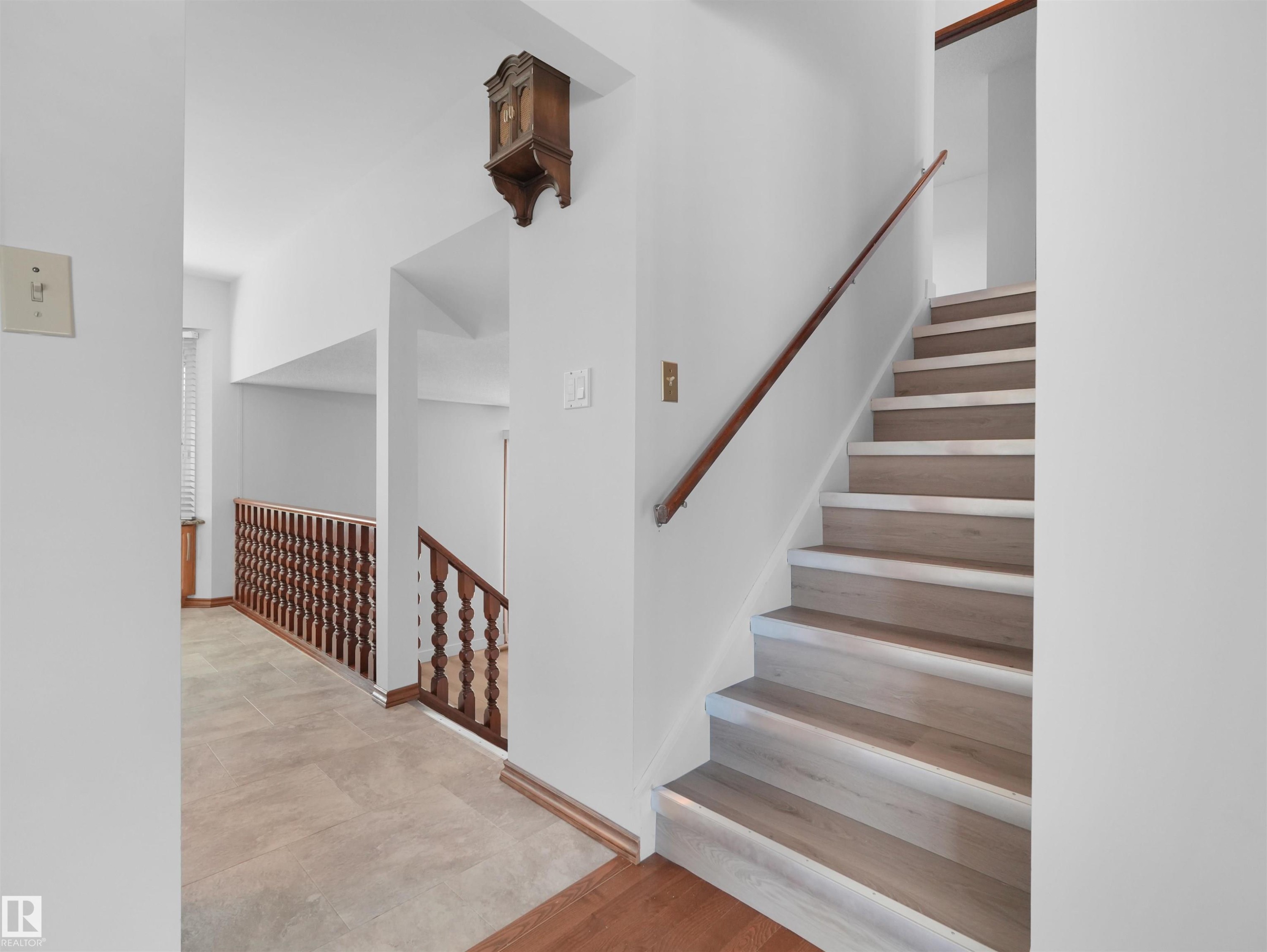 Bright, open staircase featuring wood-finish treads with gray risers and a coordinating wood handrail - 7357 18 Avenue Nw, Edmonton, AB - Indoor Photo Showing Other Room