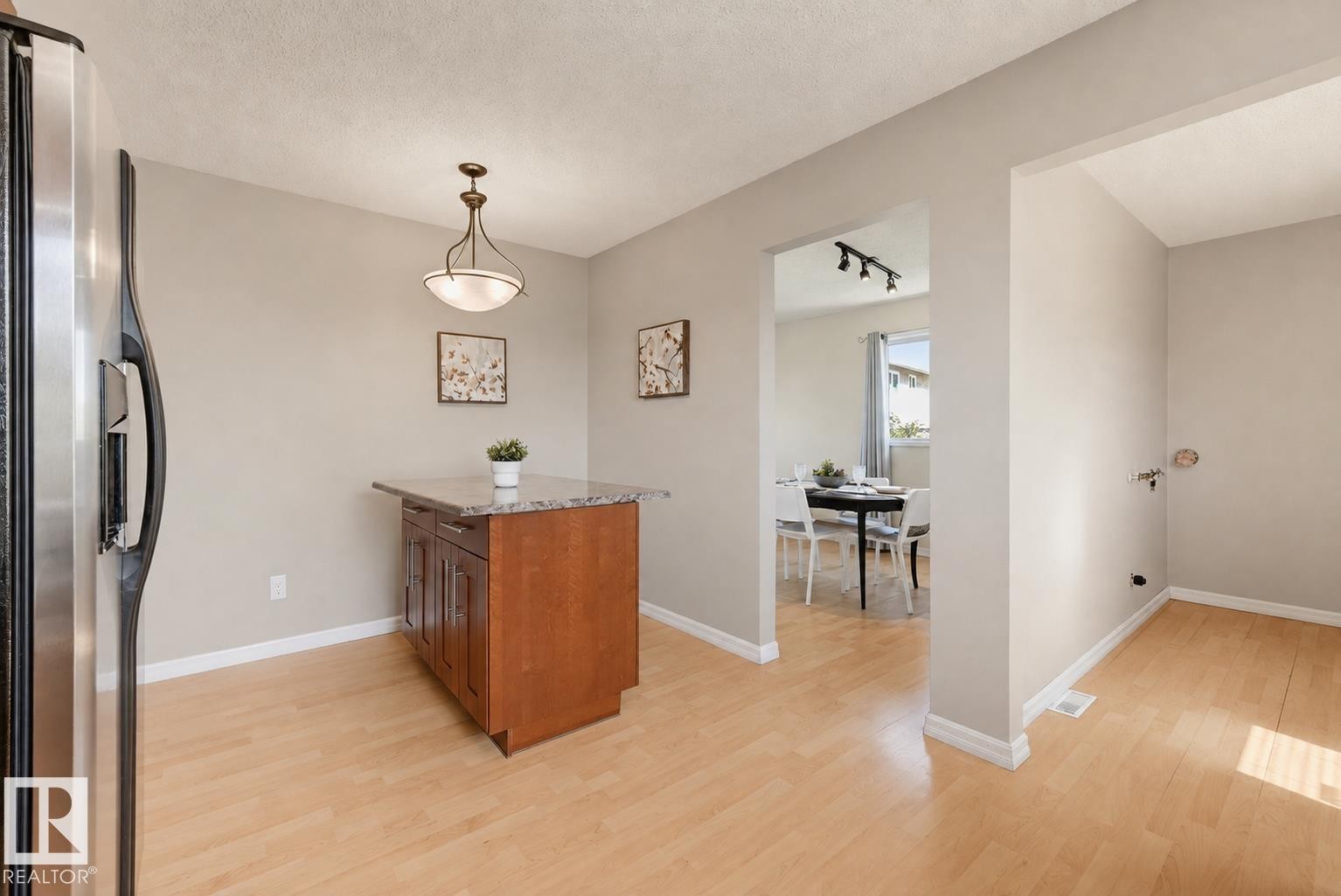 Stainless steel refrigerator, wood-finish flooring, central island with storage, pendant light fixture, and arched doorway - 6768 39 Avenue Nw, Edmonton, AB - Indoor